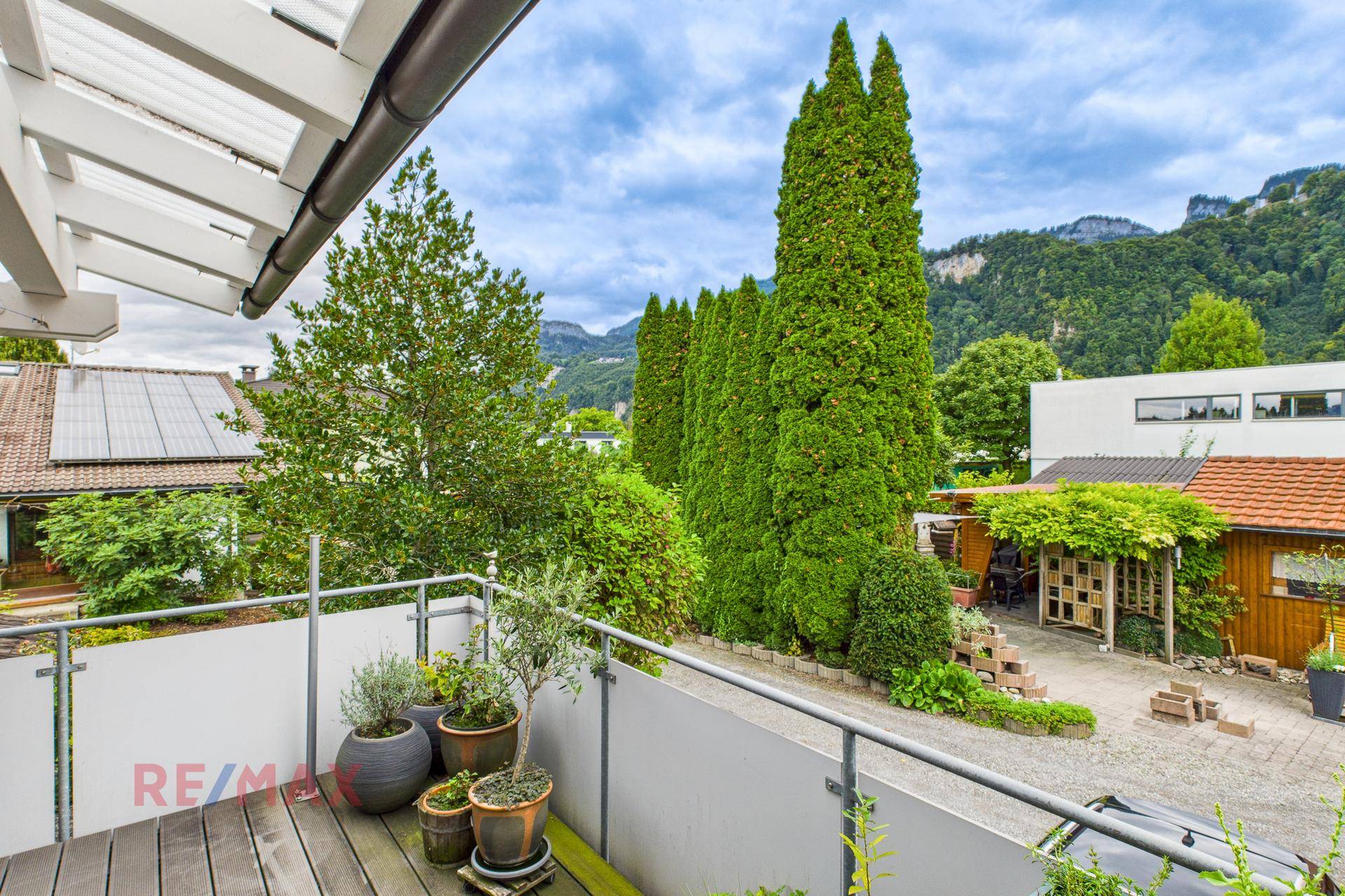 Balkon mit Holzboden, Pflanzen und weitem Blick auf die grüne Landschaft.