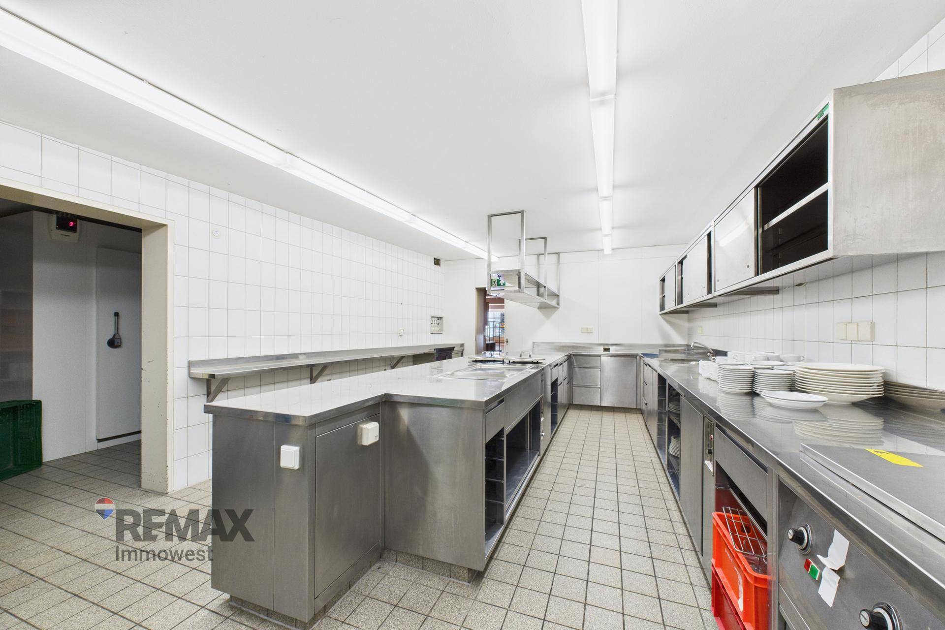 Große Industrieküche mit Edelstahlmöbeln, Fliesenboden und professioneller Ausstattung für die Gastronomie.