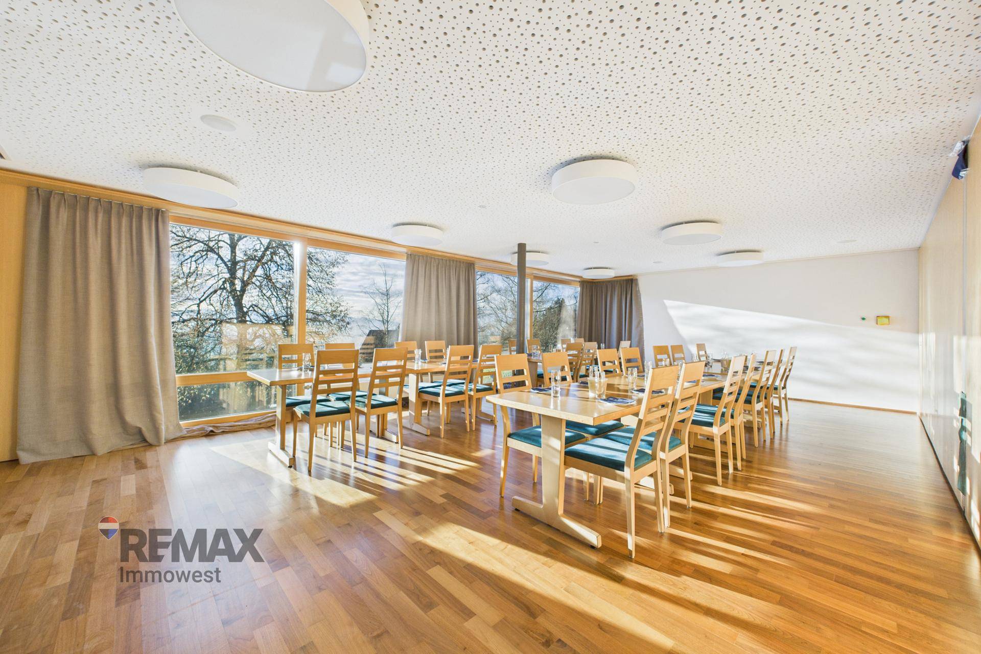 Großer Konferenz- oder Veranstaltungsraum mit vielen Tischen, Stühlen und weitem Ausblick durch Panoramafenster.