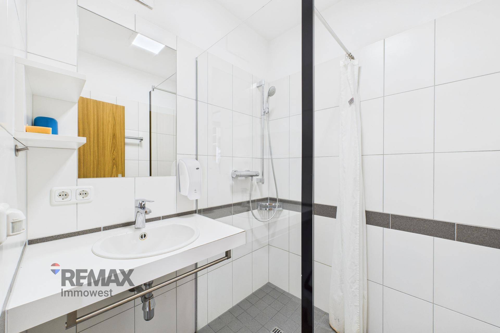 Helles Badezimmer mit Duschkabine, Waschbecken und weißen Fliesen, modern und funktional gestaltet.