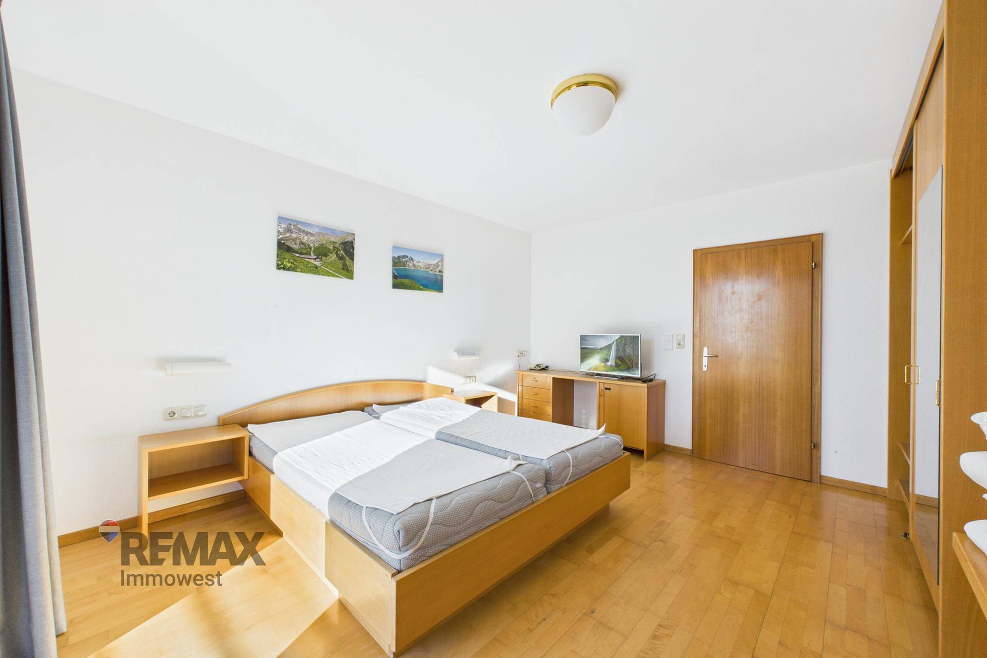 Gemütliches Schlafzimmer mit Doppelbett, Holzmöbeln und einem Fernseher, ideal für Entspannung.