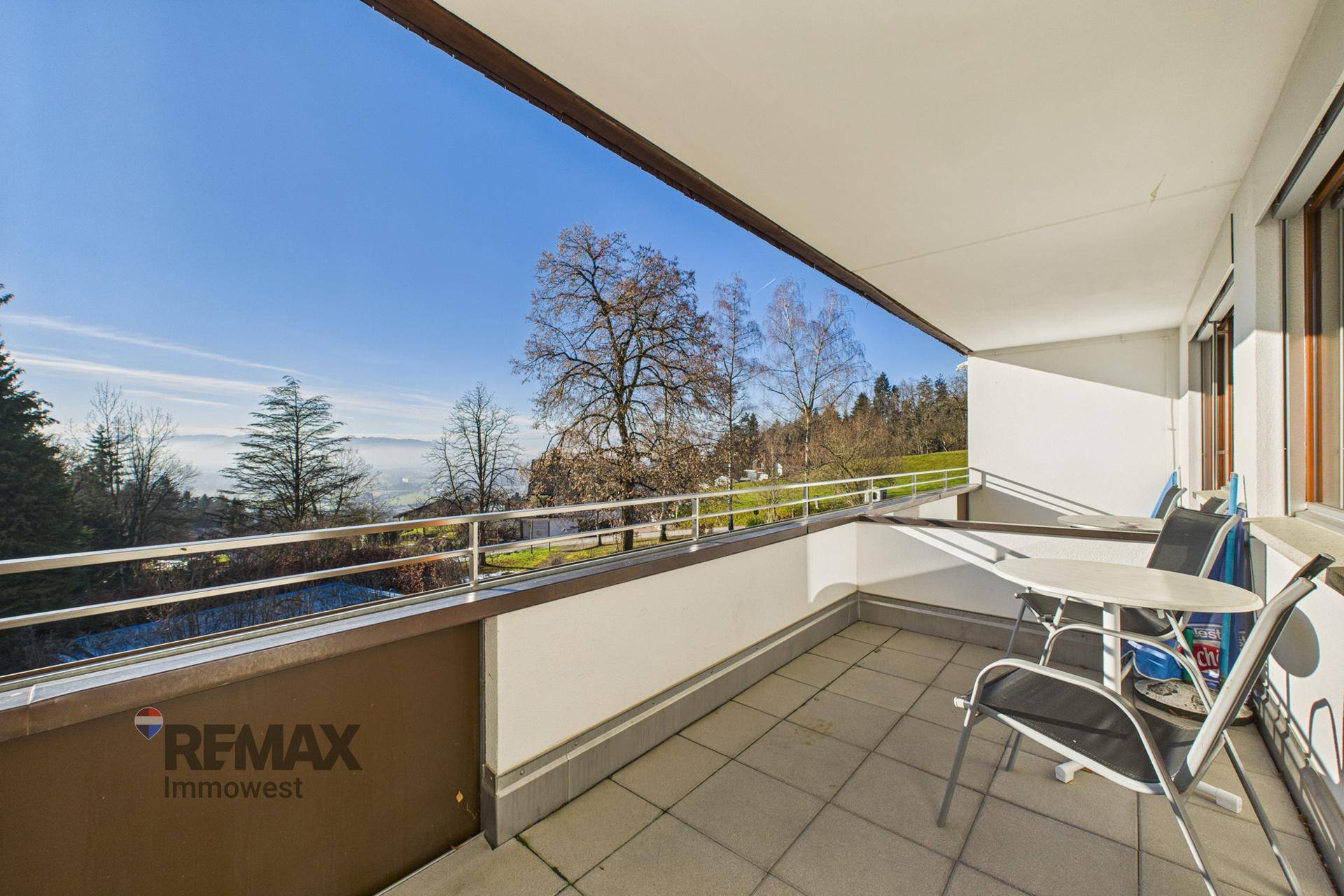 Sonniger Balkon mit Fliesenboden und Sitzgelegenheiten, bietet einen weiten Blick über die Landschaft.