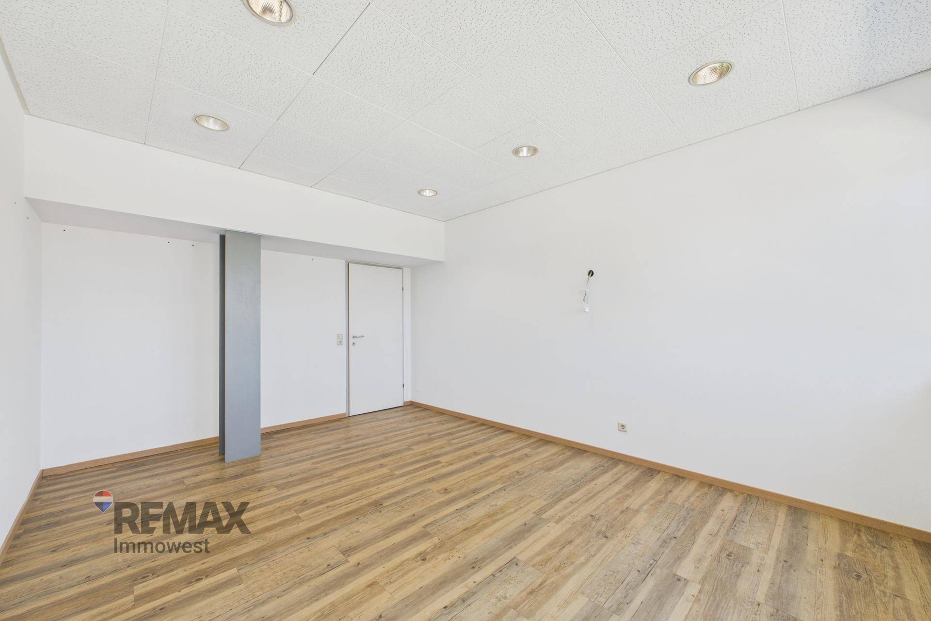 Leeres Büro mit hellem Holzboden und weiß gestrichenen Wänden, bereit für neue Mieter.