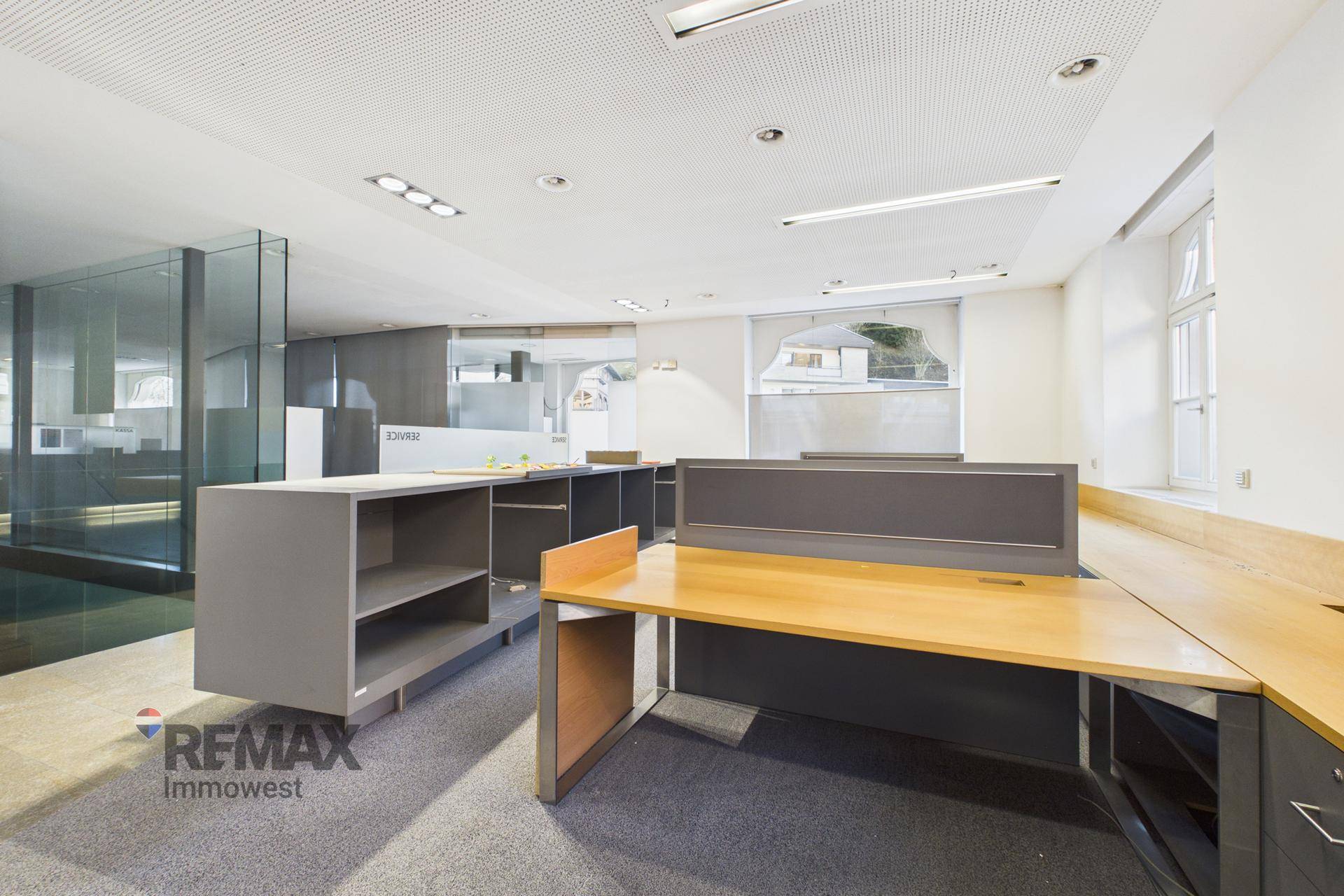 Offener Bürobereich mit modularen Möbeln, Teppichboden und Glaswänden, die den Raum strukturieren.