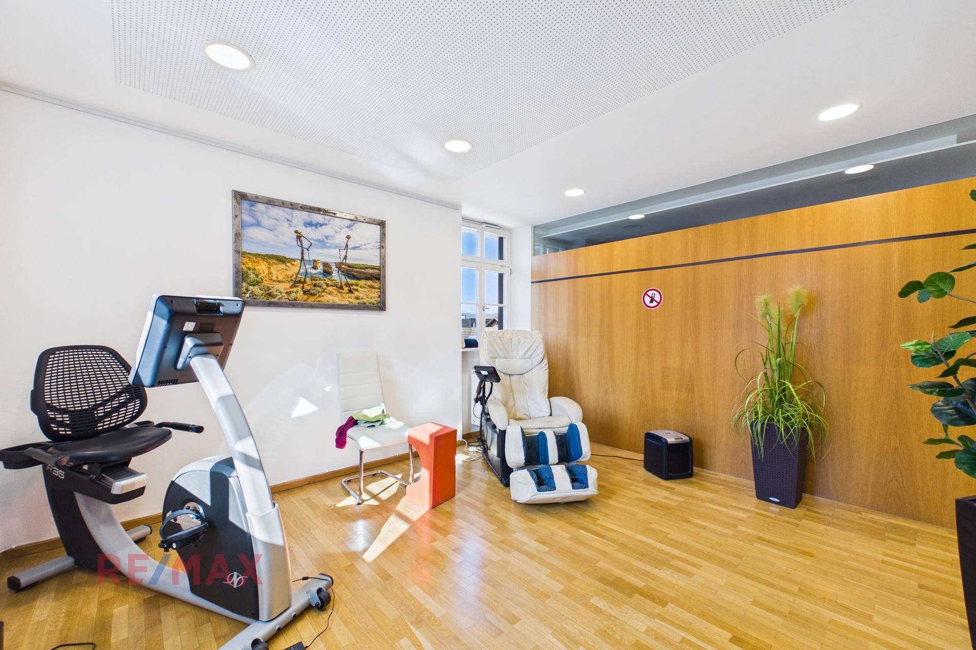 Therapieraum mit Trainingsgerät, Massagesessel und warmer Holzverkleidung, schafft eine angenehme Atmosphäre.