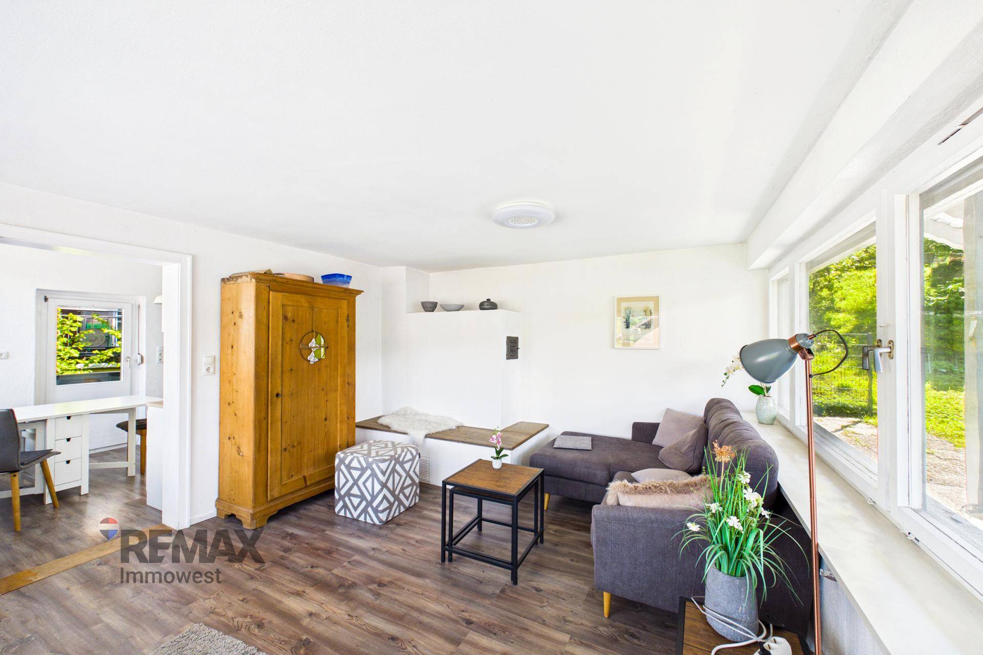 Gemütliches Wohnzimmer mit Sofa, Holzschrank und Blick auf die grüne Umgebung.