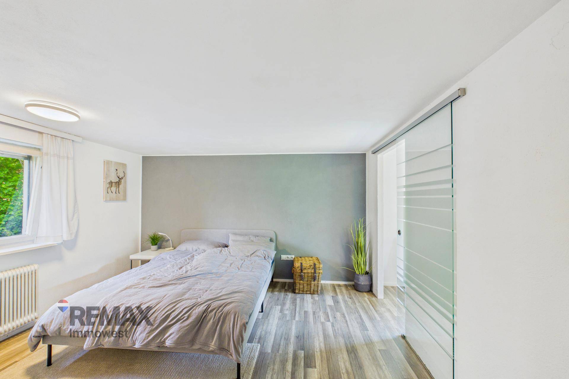 Schlafzimmer mit Doppelbett, grauer Akzentwand und Holzboden.