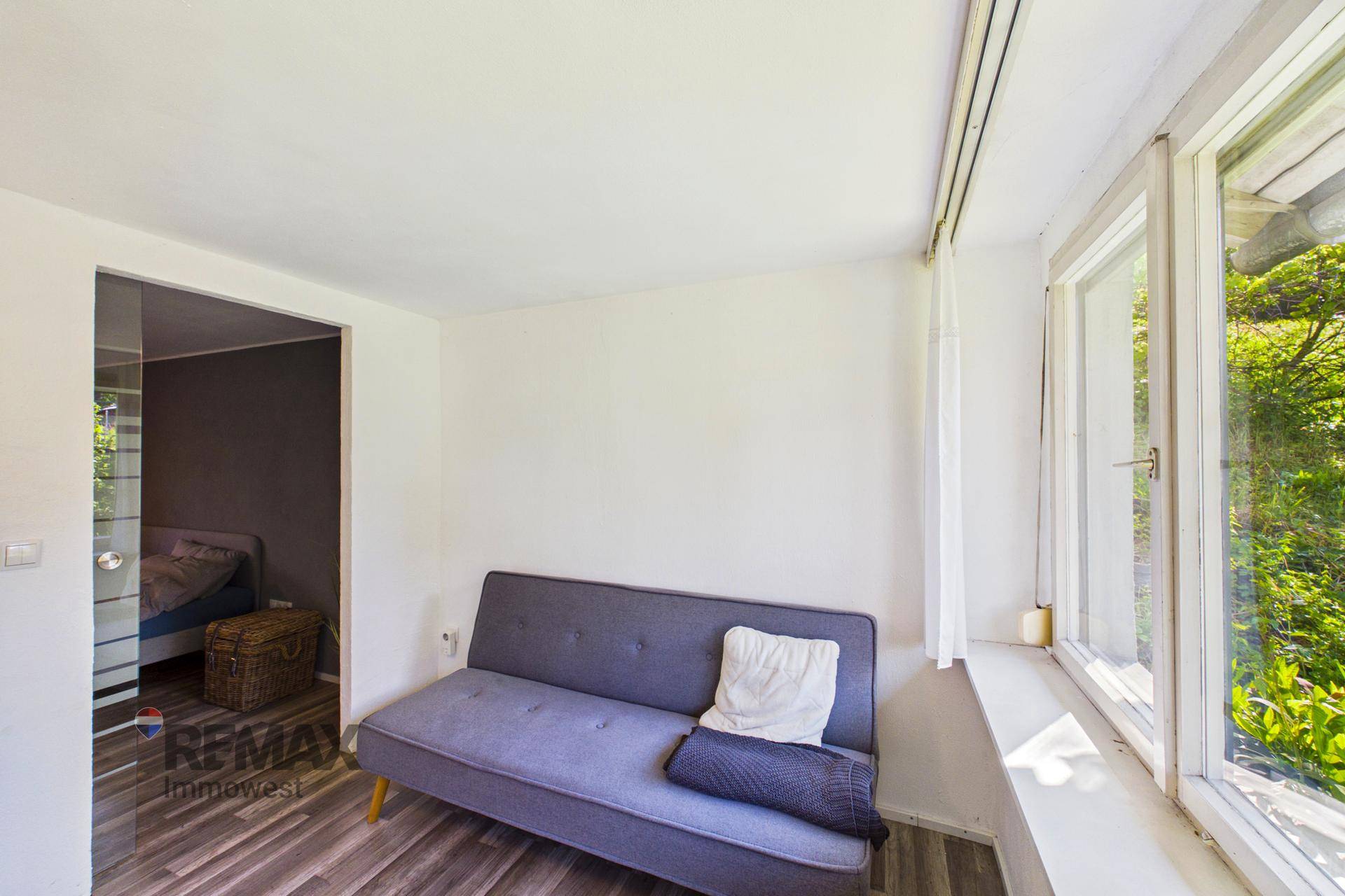 Kleines Schlafzimmer mit Sofa und Zugang zu einem weiteren Schlafbereich.