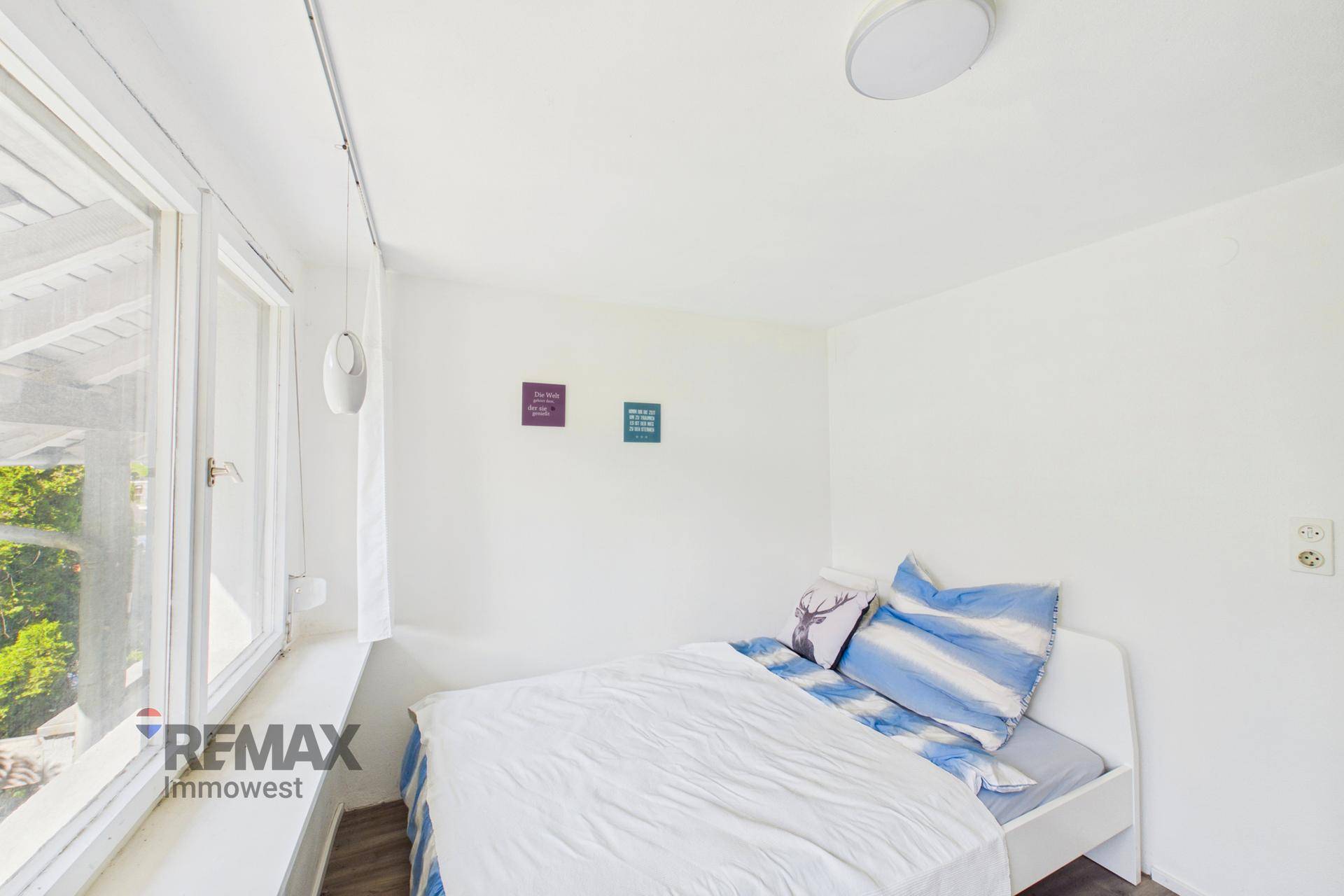 Kinderzimmer mit Einzelbett, Fenster und einfacher, heller Einrichtung.