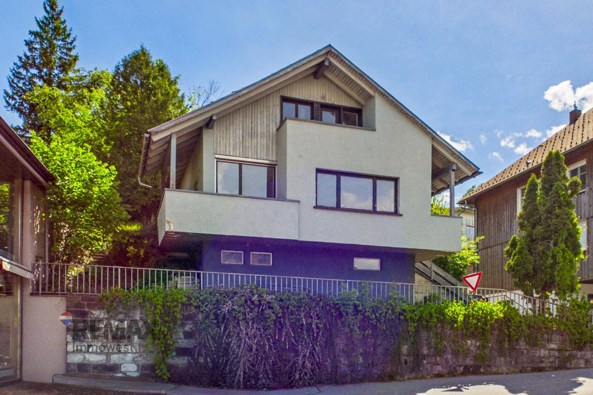 Freistehendes Haus mit Satteldach und moderner Fassade, umgeben von Bäumen und Grünflächen.