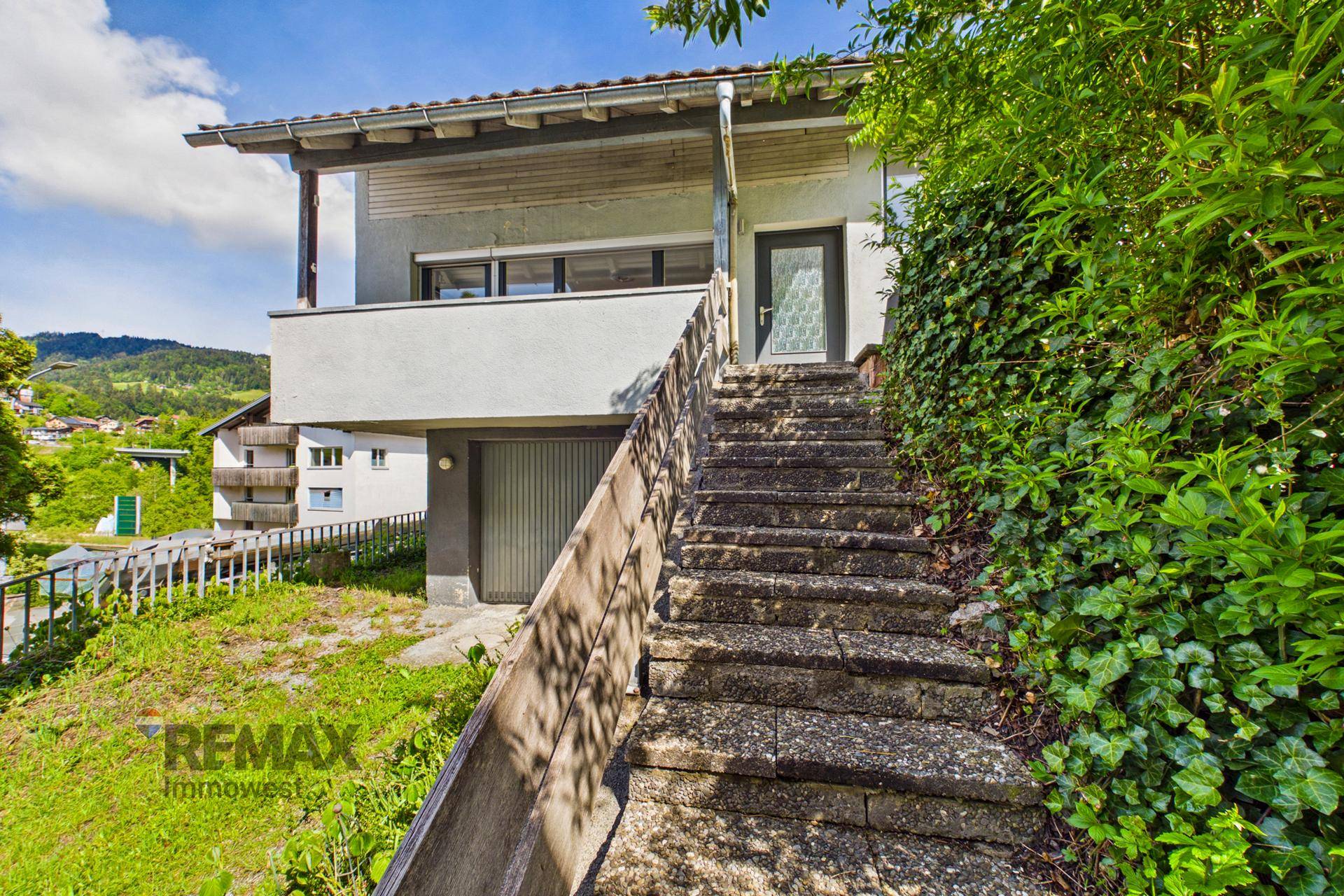 Eingangsbereich des Hauses mit Steintreppe und Garage im Untergeschoss.