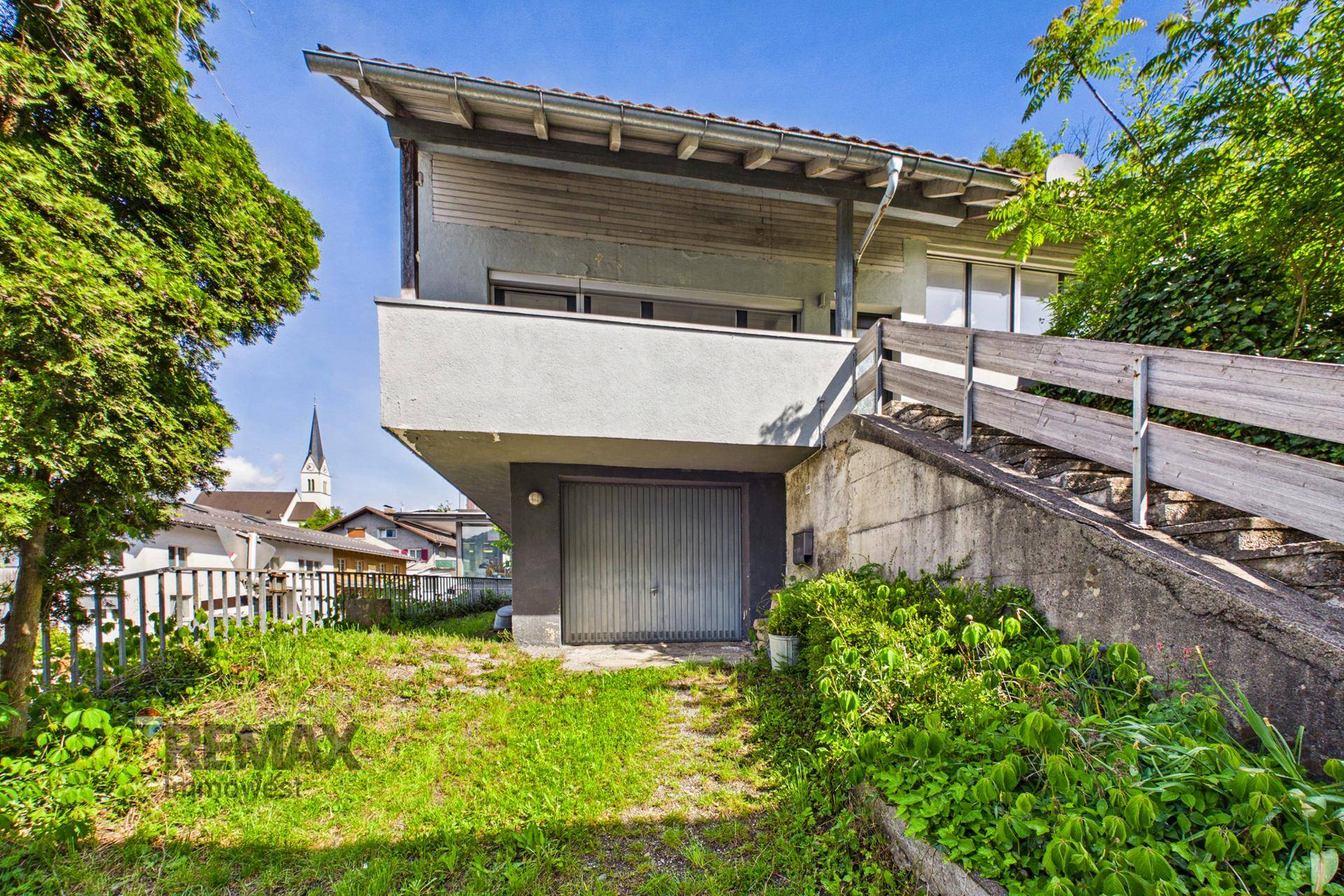 Ansicht des Hauses von unten mit Garage und Treppe, umgeben von Natur.