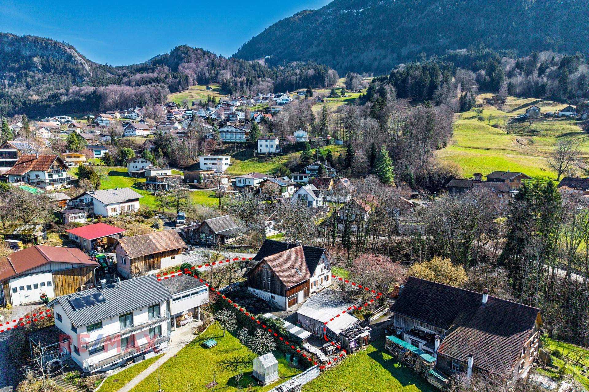 Luftaufnahme des Anwesens mit Nebengebäuden und der umliegenden Berglandschaft im Hintergrund.