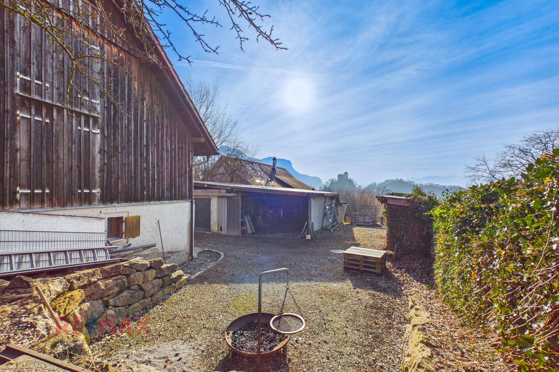 Gartenbereich mit Feuerstelle und Hecke, ideal für gemütliche Abende im Freien.