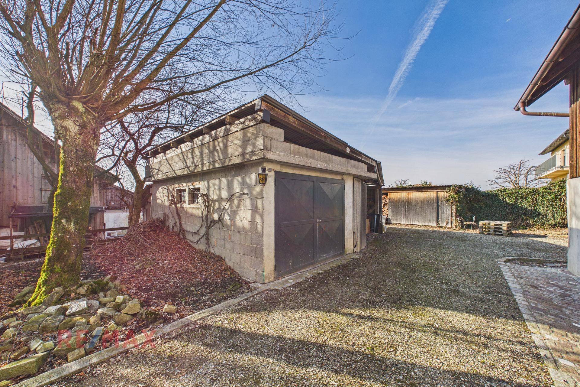 Freistehende Garage aus Betonblöcken mit Doppeltor und angrenzendem Schuppenbereich.