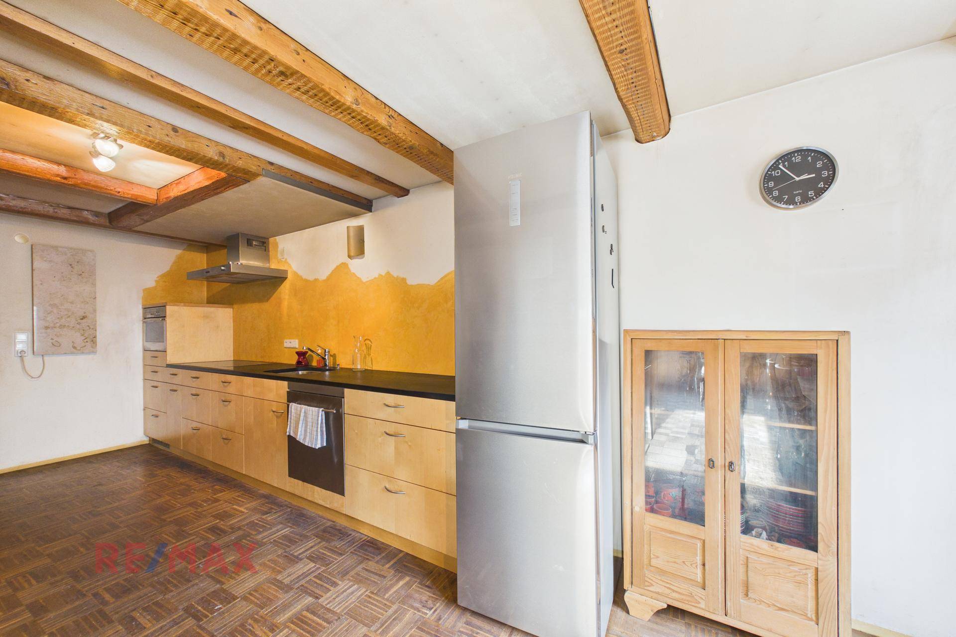Rustikale Küche mit Holzbalken, Holzboden und gelb gestrichener Wand, ausgestattet mit Kühlschrank.