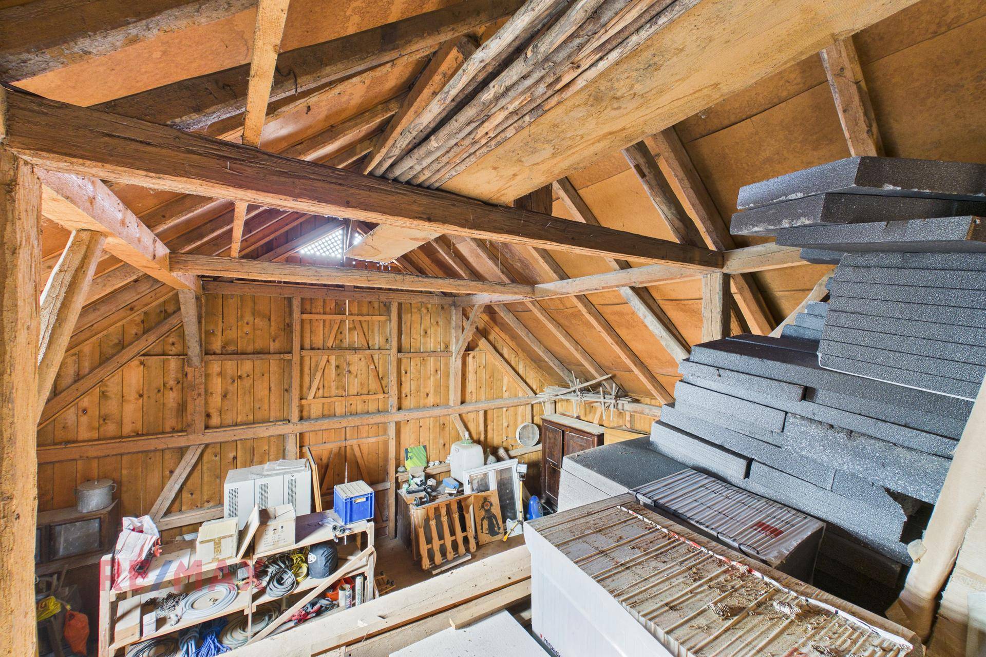 Blick auf den weitläufigen Dachboden mit robusten Holzbalken und viel Stauraum für diverse Gegenstände.