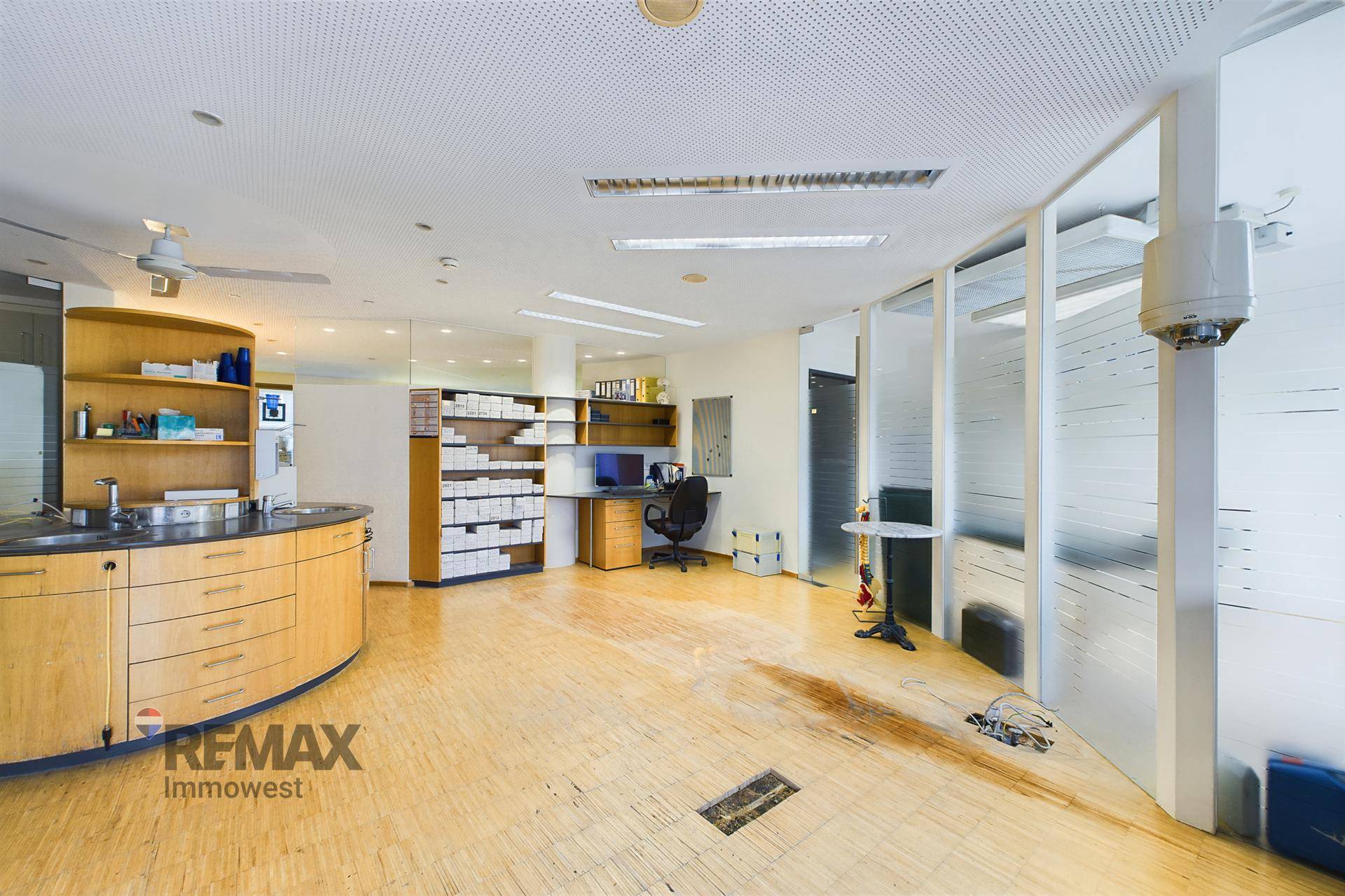 Geräumiger Bürobereich mit runder Arbeitsstation, Regalen und gläsernen Trennwänden.