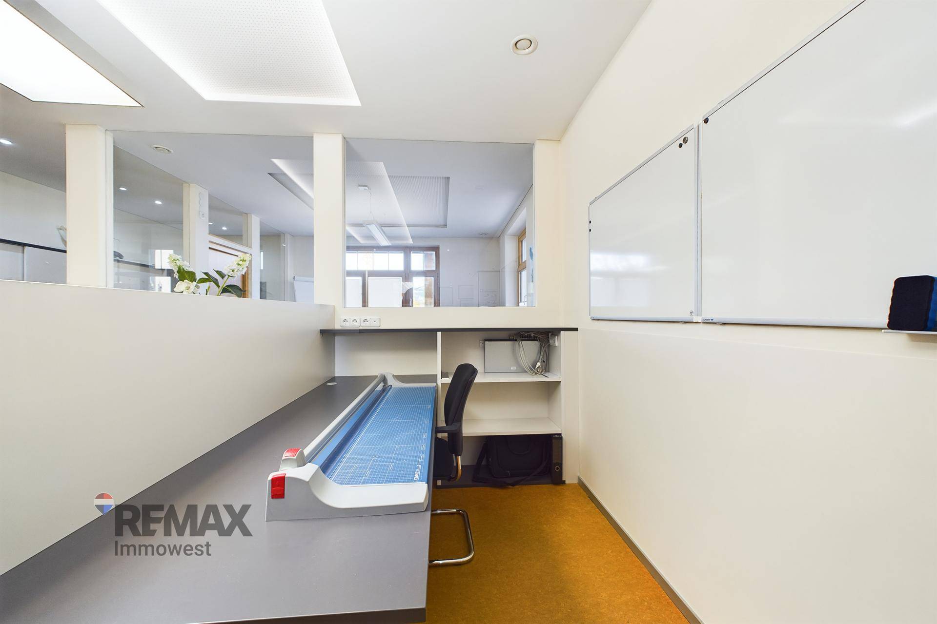 Detailansicht eines Arbeitsbereichs im Büro mit einem großen Tisch, Whiteboards und Linoleumboden.
