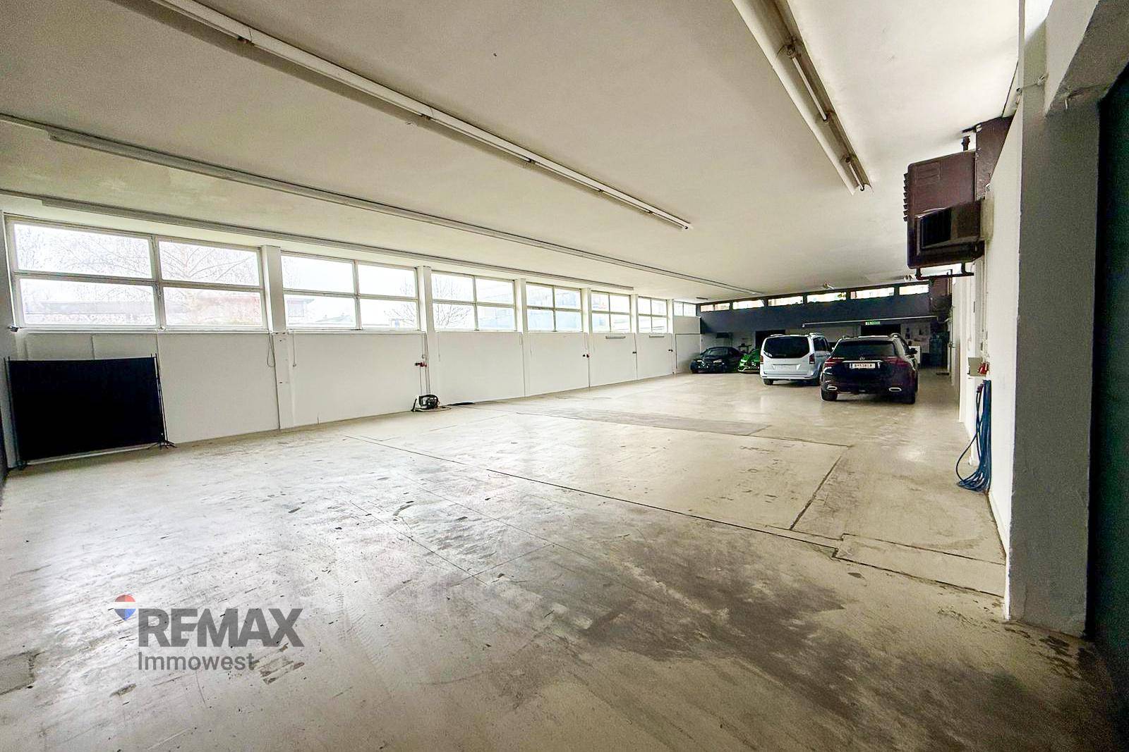 Weitläufige Produktionshalle mit Betonboden und Tageslicht durch Fensterbänder.