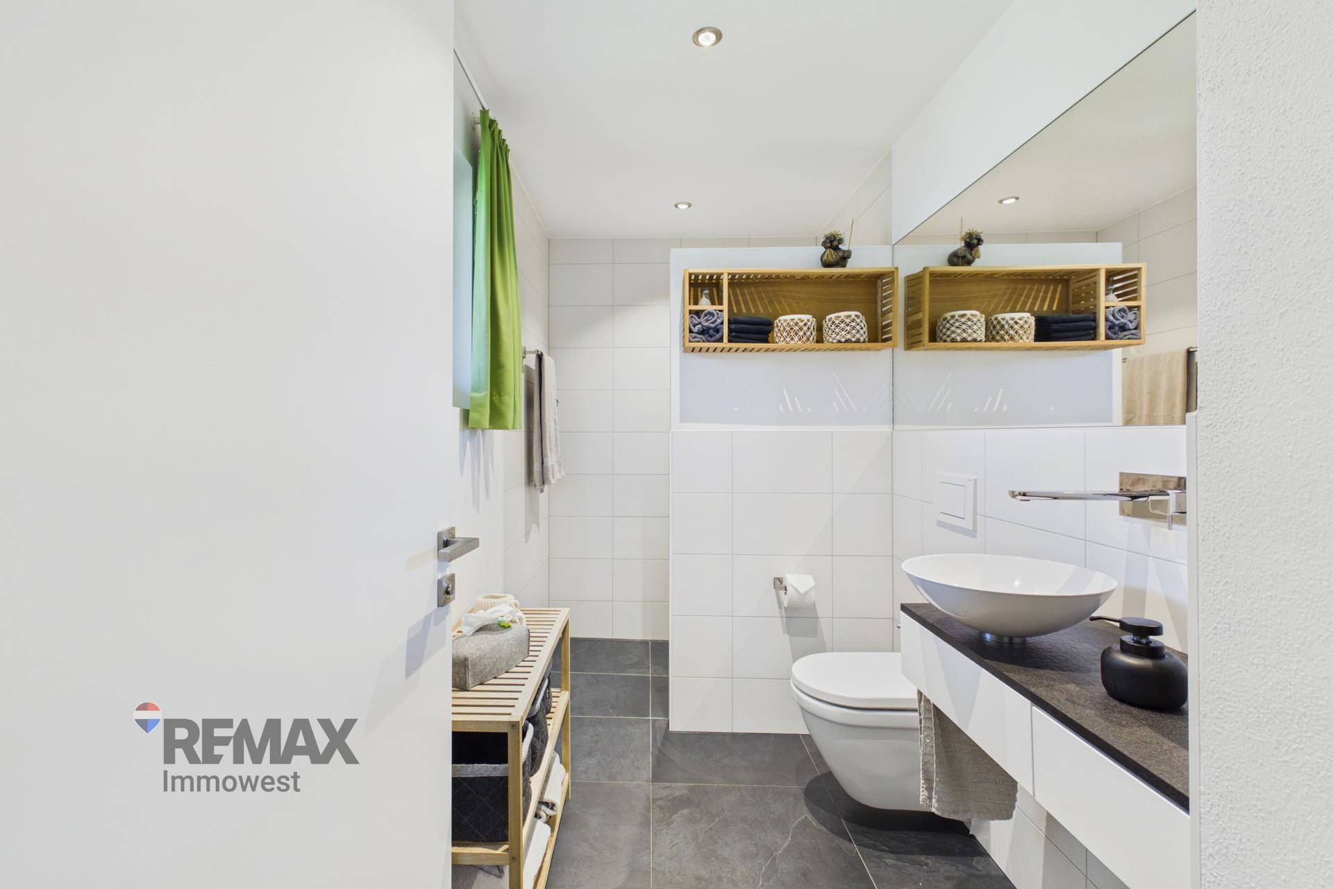 Modernes Badezimmer mit weißer Wandverkleidung, dunklen Bodenfliesen und Aufsatzwaschbecken.