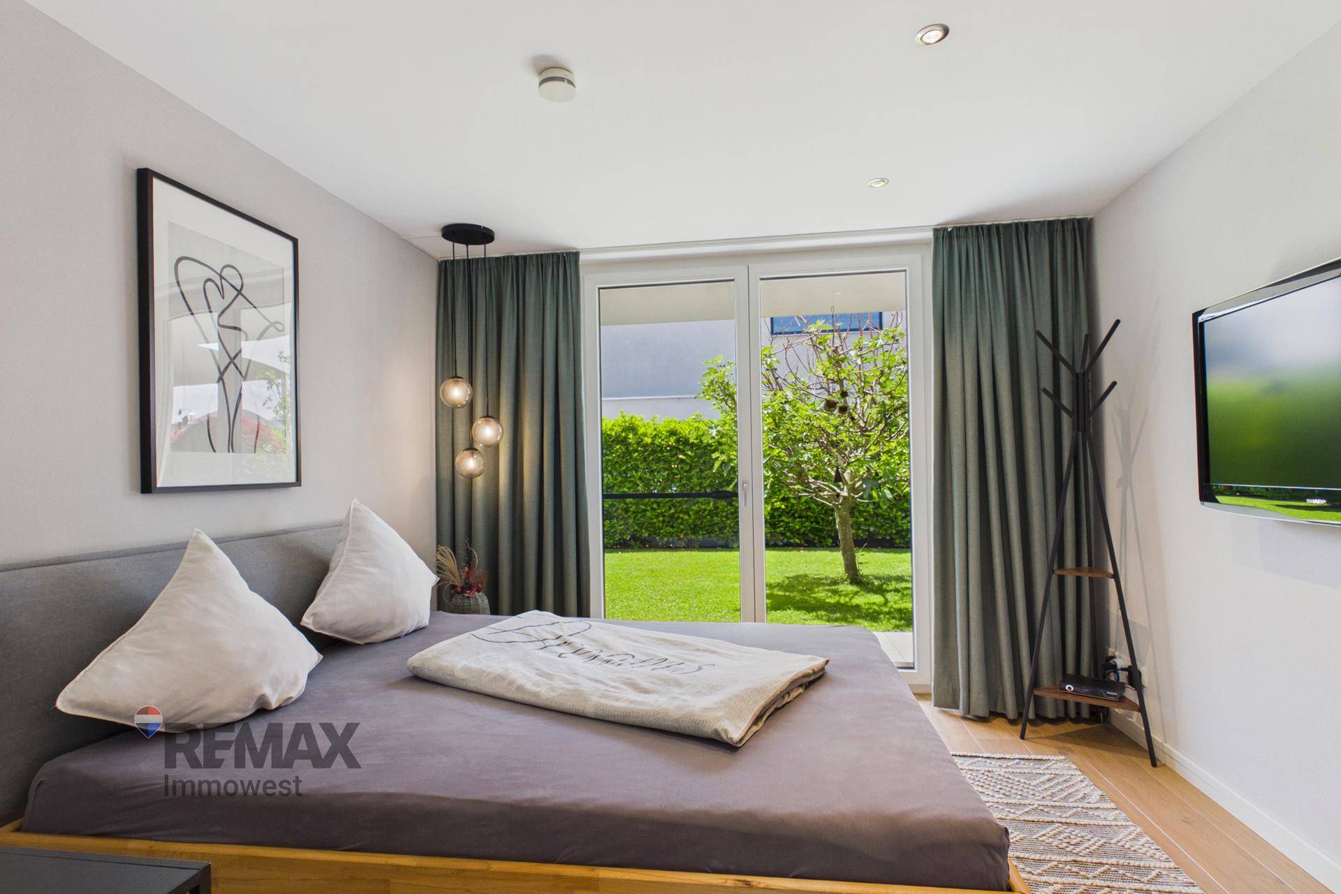 Gemütliches Schlafzimmer mit Holzboden, großem Bett und direktem Zugang zum Garten.