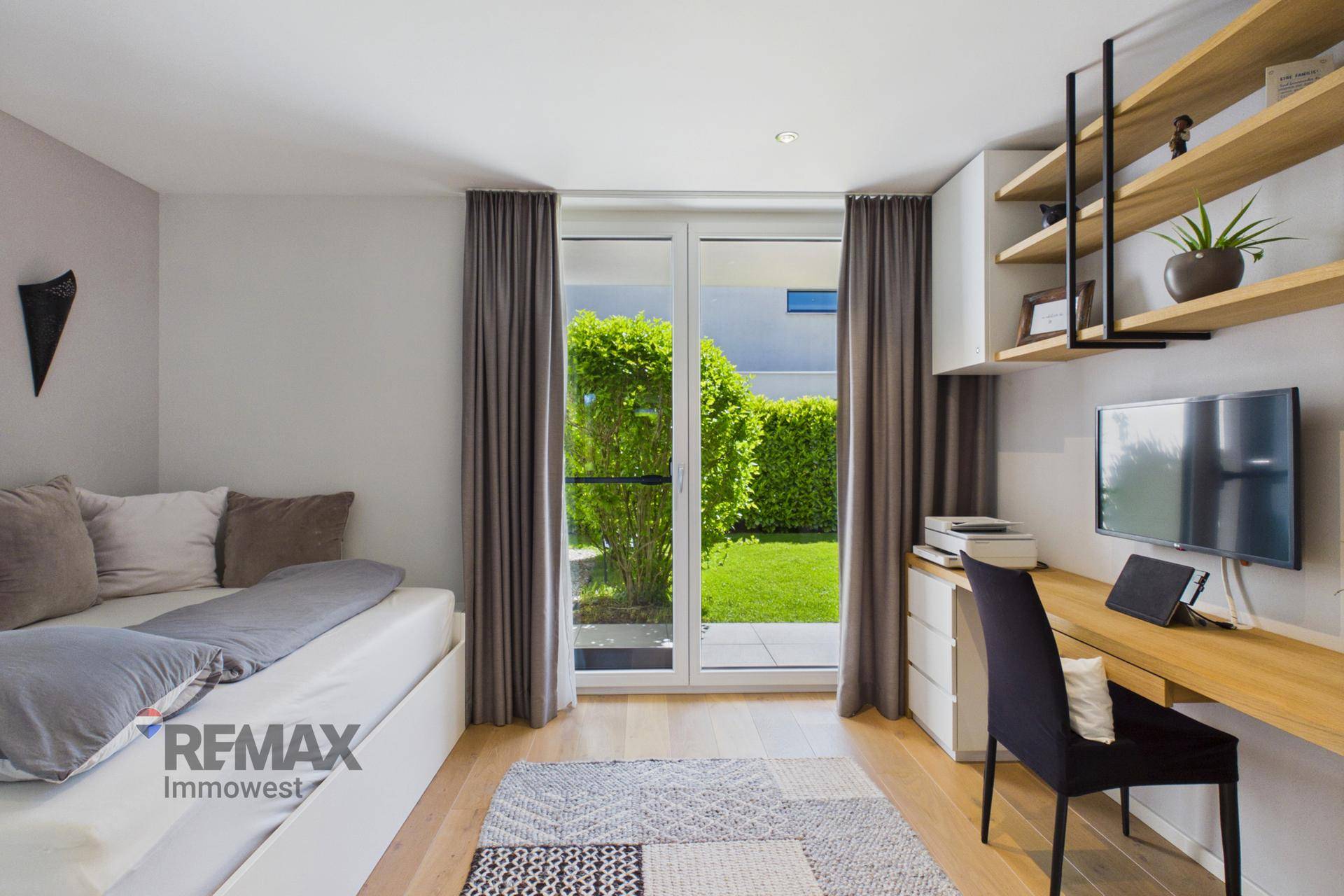 Helles Zimmer mit Holzboden, Schreibtisch und Blick ins Grüne, ideal als Gäste- oder Arbeitszimmer.