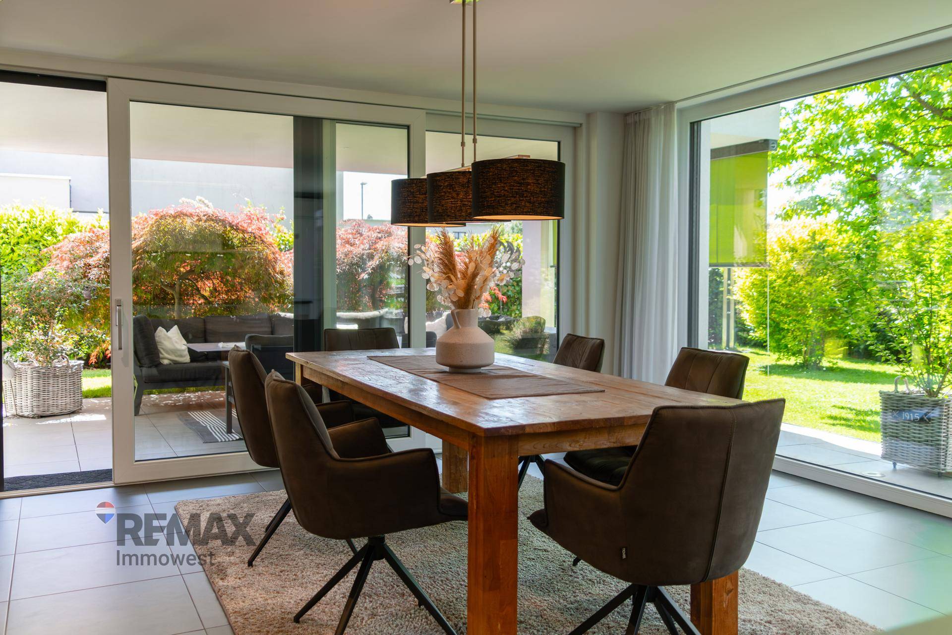 Heller Essbereich mit großem Holztisch, modernen Stühlen und Zugang zur überdachten Terrasse.