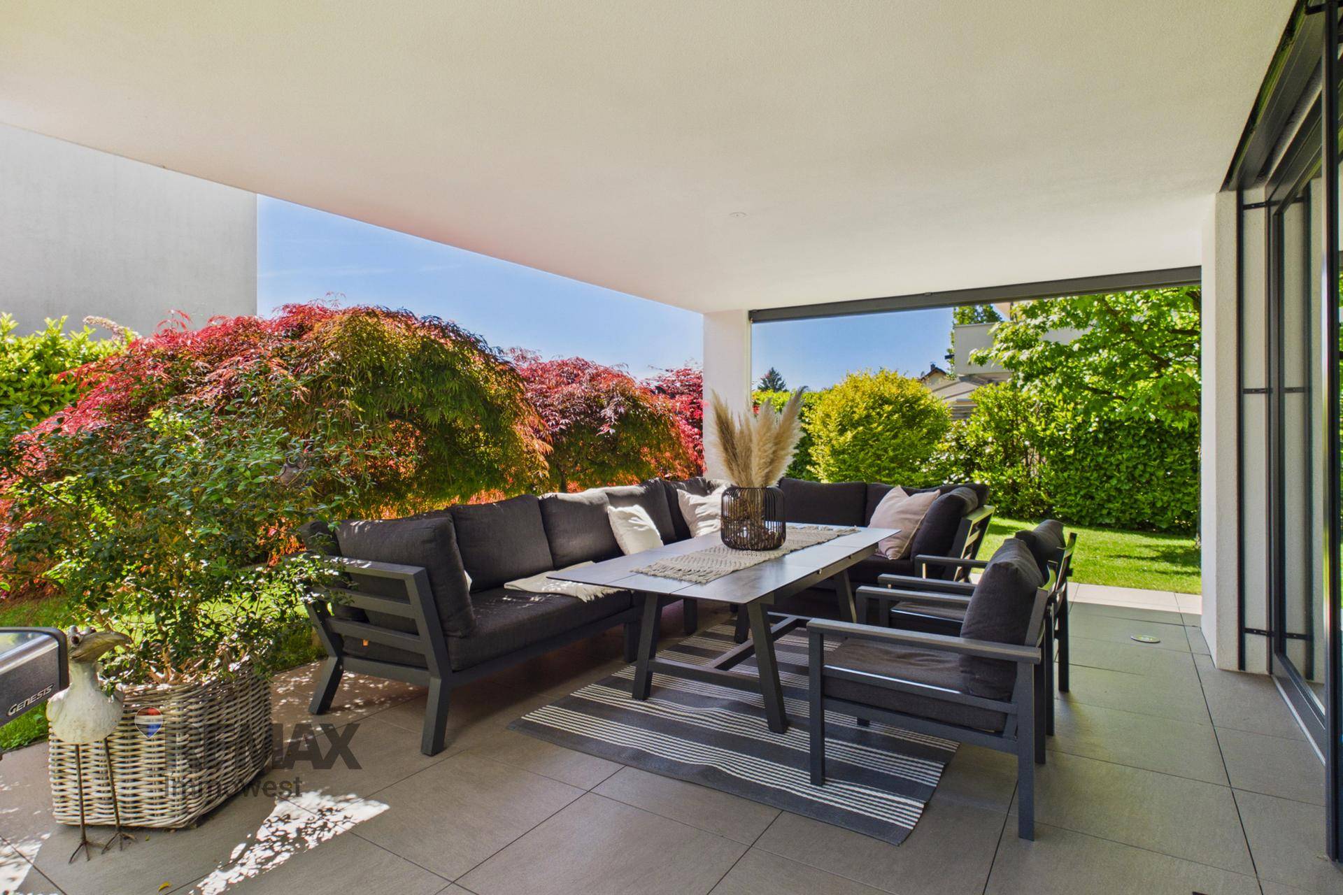 Überdachte Terrasse mit bequemen Lounge-Möbeln und Blick auf den gepflegten Garten.