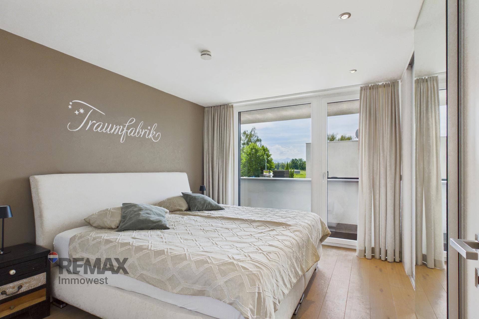 Geräumiges Schlafzimmer mit Doppelbett, Holzboden und Zugang zu einem Balkon.