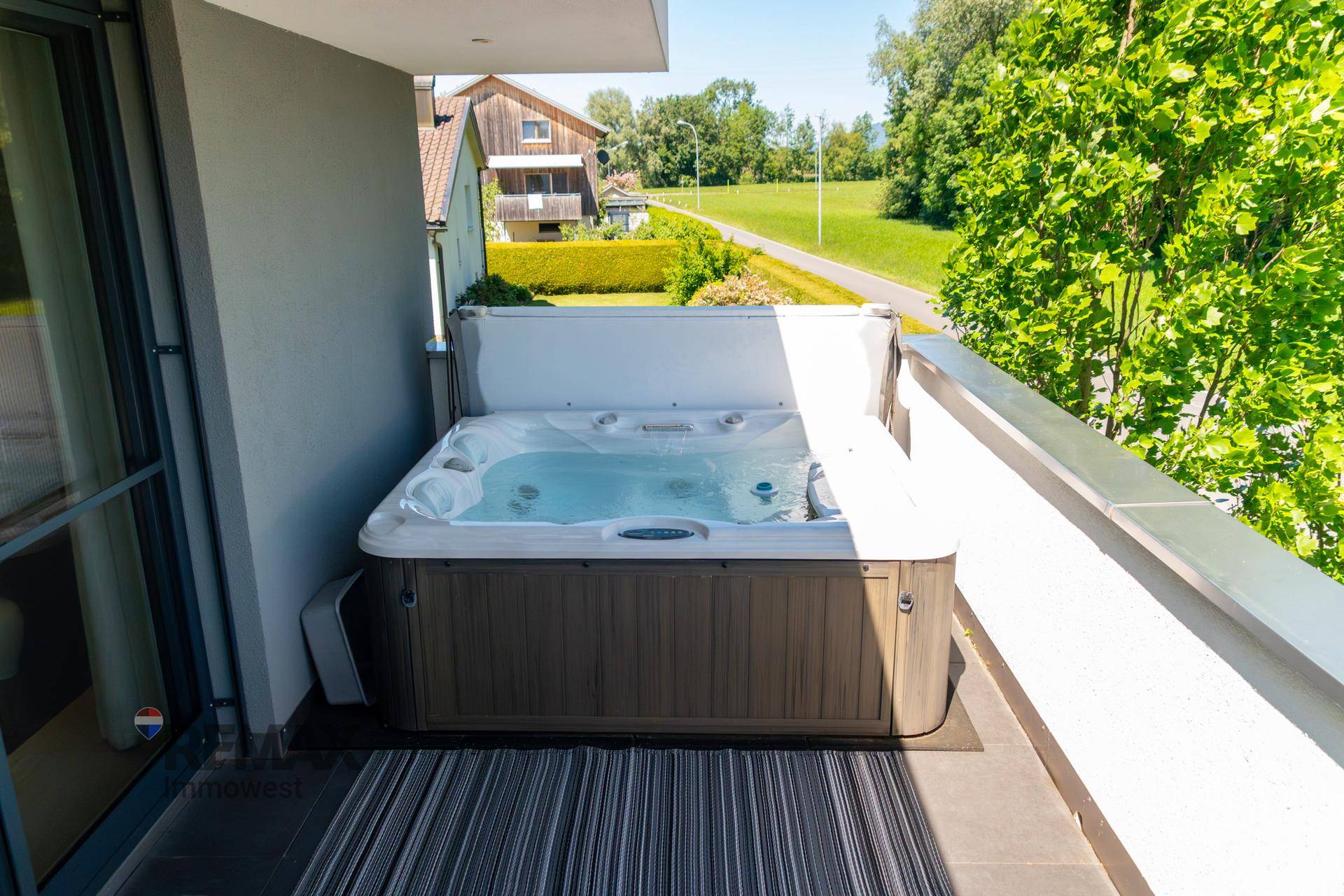 Sonniger Balkon mit Whirlpool und Blick auf die umliegende Natur und Landschaft.