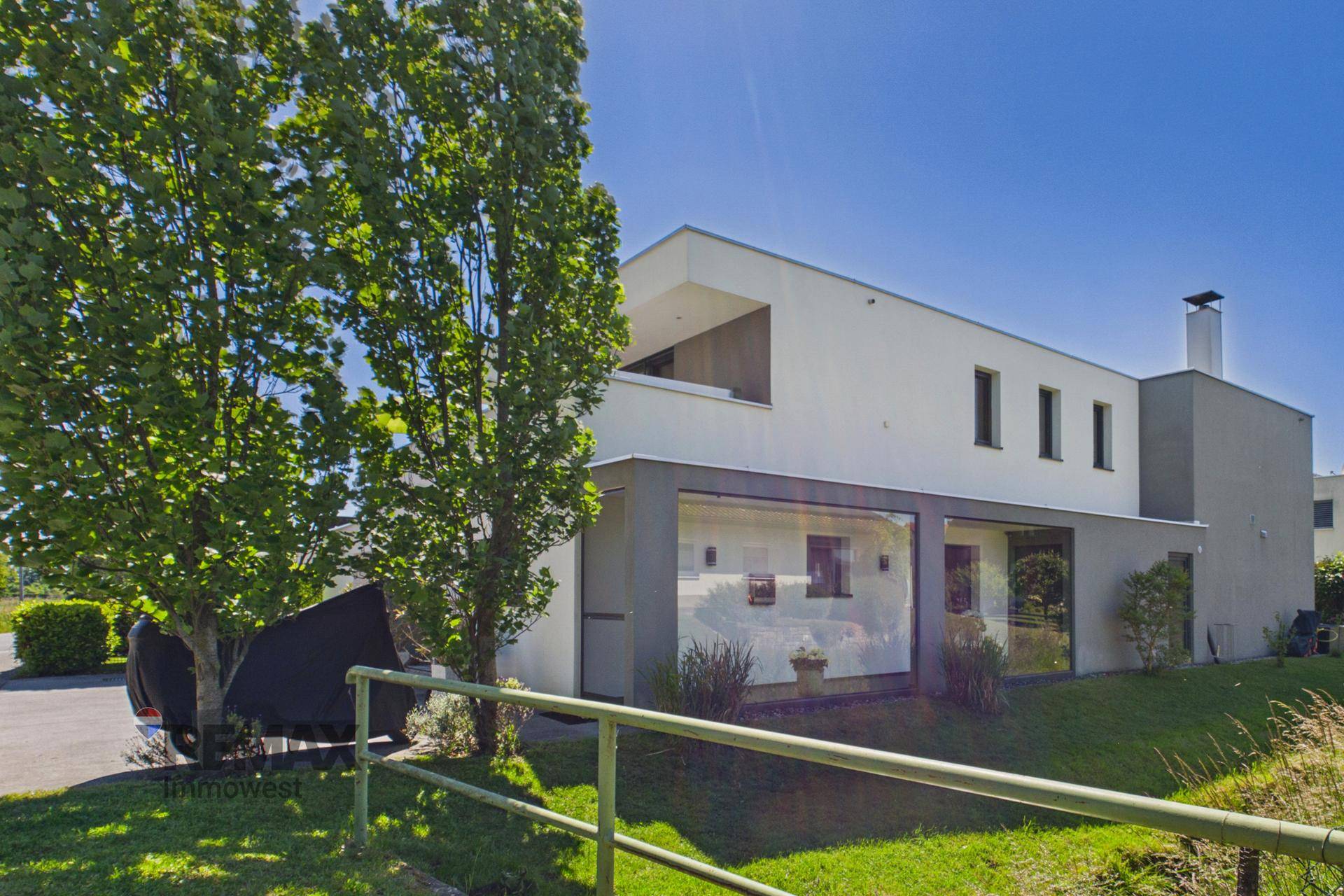 Moderne Architektur des Hauses mit großen Fenstern und gepflegtem Vorgarten.