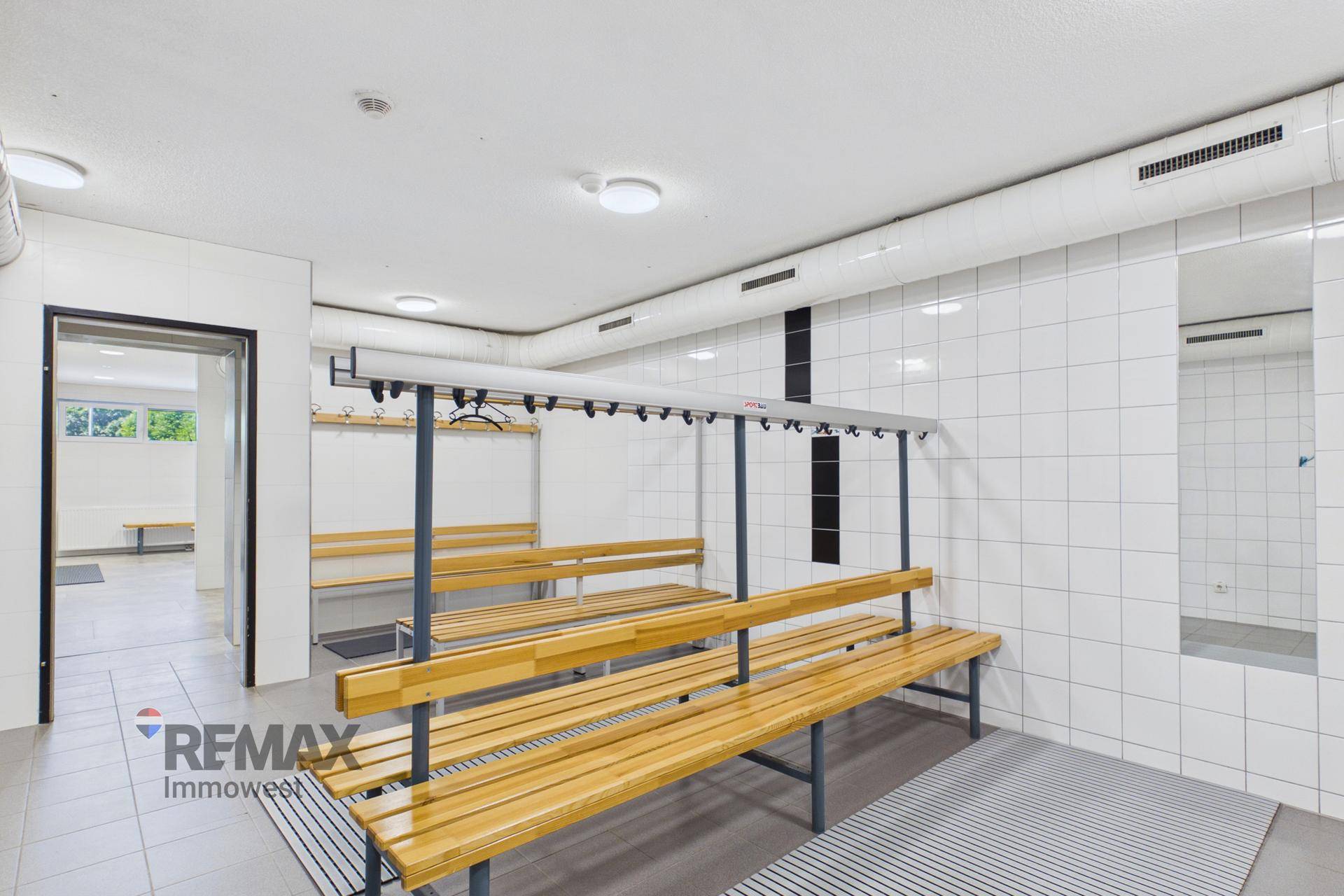 Geräumiger Umkleideraum mit Holzbänken und Kleiderhaken, ideal für Sport- oder Freizeiteinrichtungen.