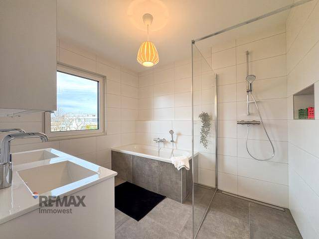 Modernes Badezimmer mit Doppelwaschbecken, Badewanne und ebenerdiger Dusche.