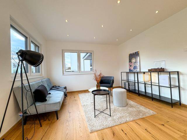 Modern eingerichtetes Wohnzimmer mit Holzboden, Sofa und dekorativen Elementen.
