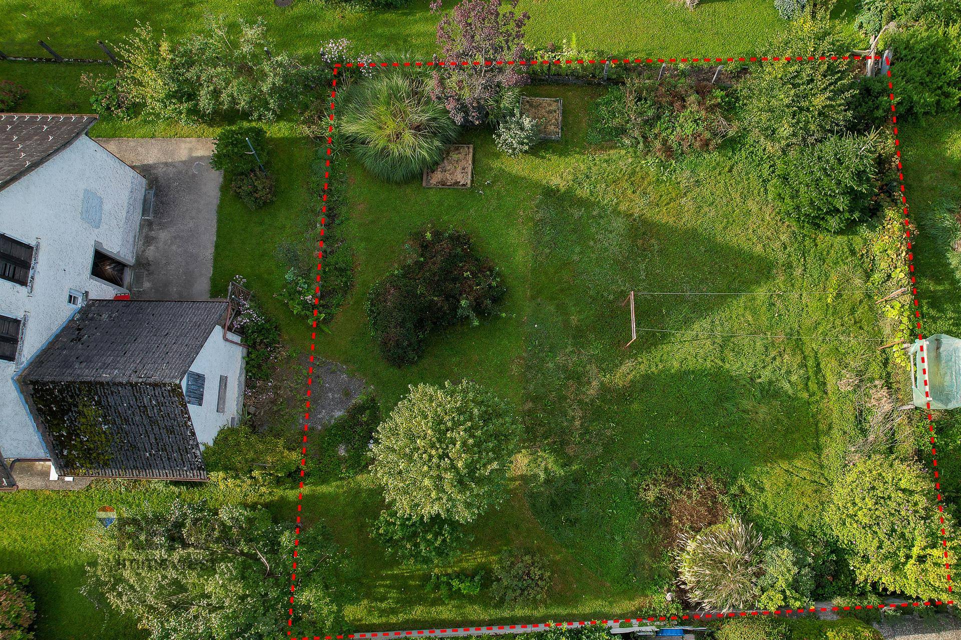 Luftaufnahme eines großen Gartengrundstücks mit viel Grünfläche und Bäumen.