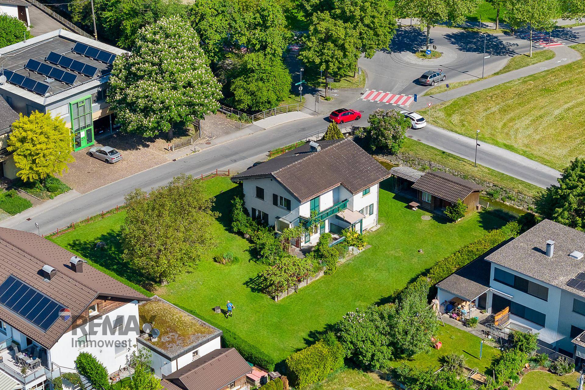 Luftaufnahme eines Hauses mit großem grünen Garten, umgeben von Bäumen und einer ruhigen Wohngegend.