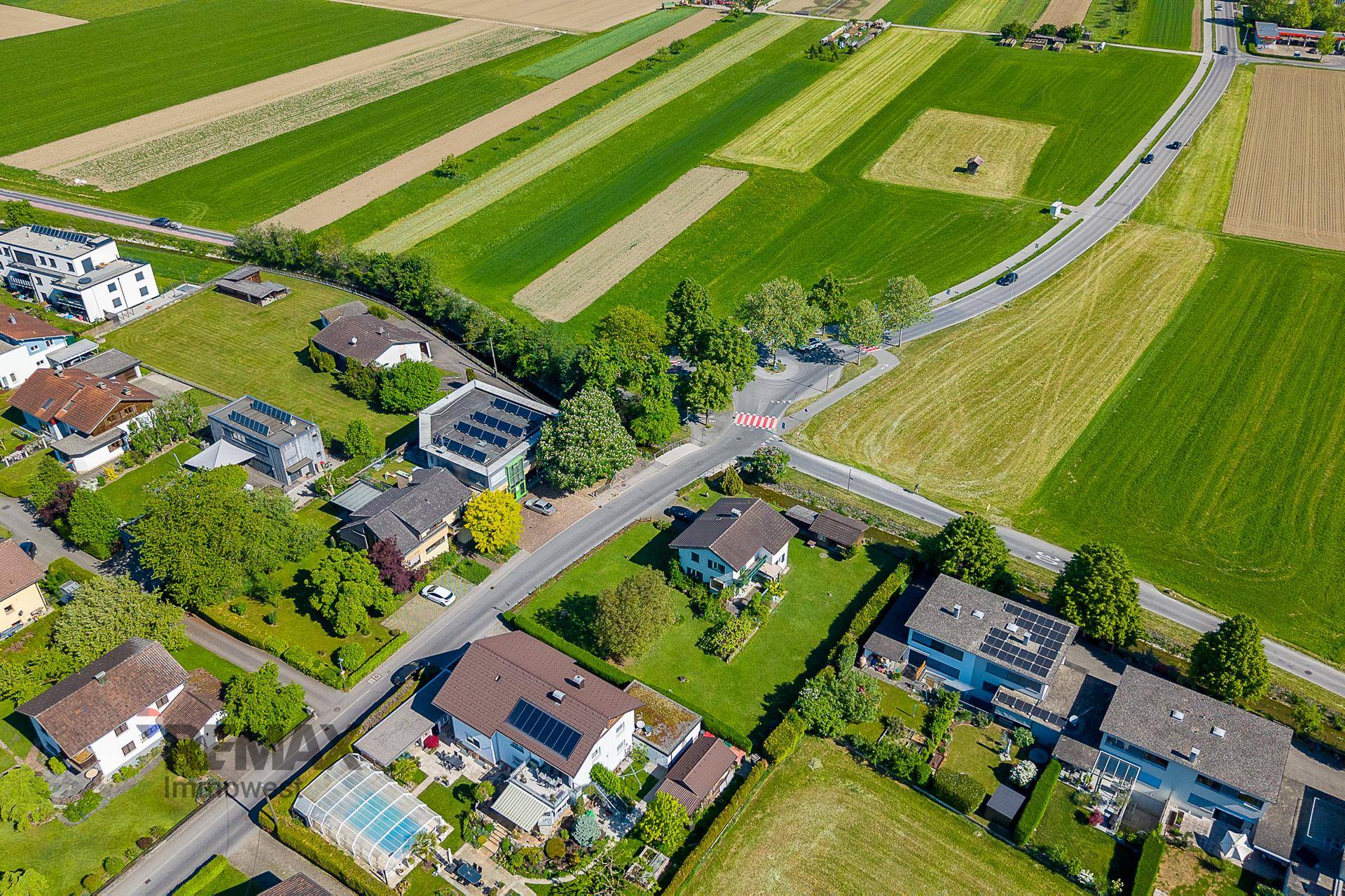 Weitläufige Luftaufnahme einer Wohnsiedlung, umgeben von grünen Feldern und ländlicher Landschaft.
