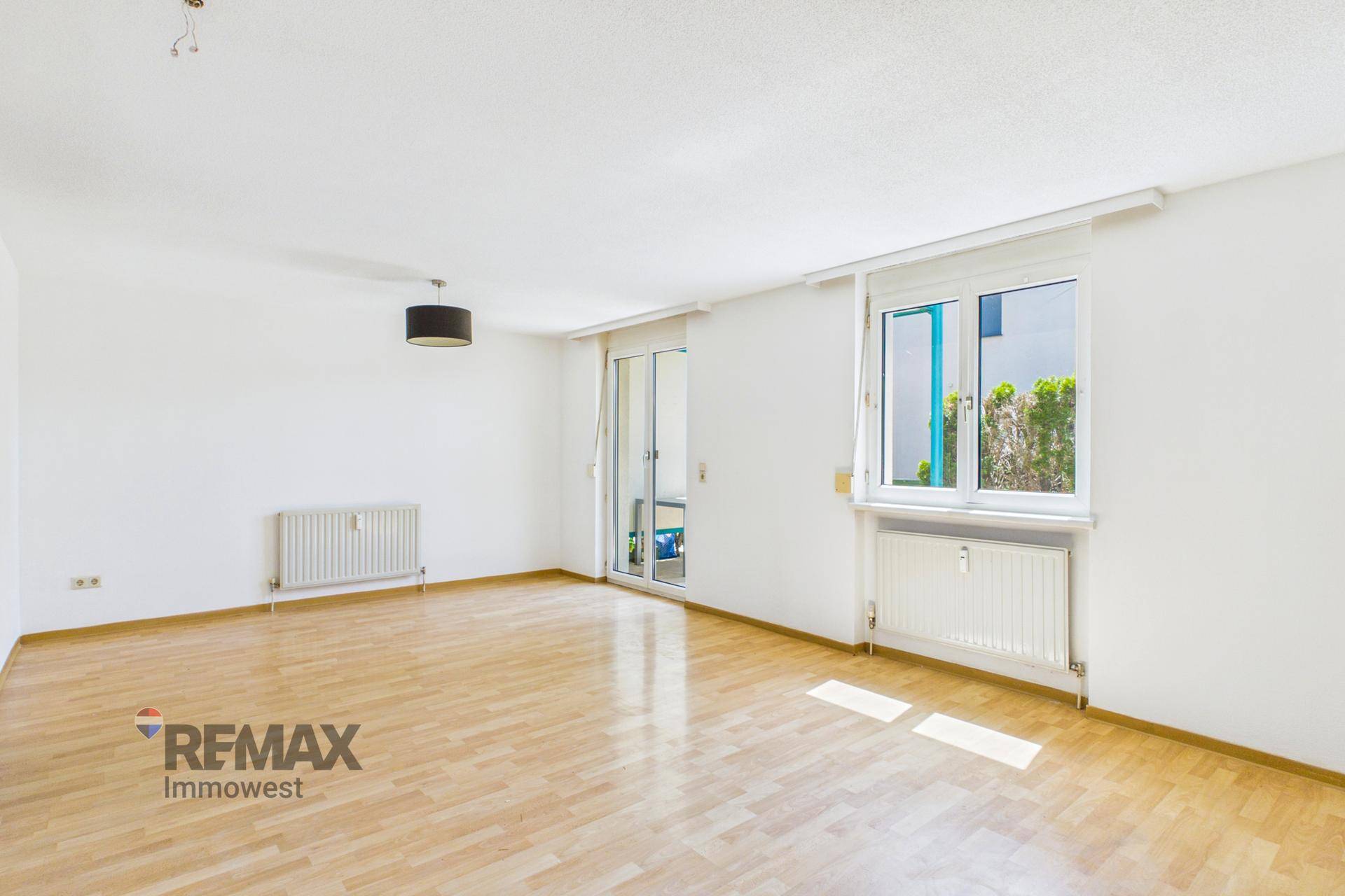 Geräumiges Wohnzimmer mit hellem Parkettboden und Zugang zur Terrasse oder zum Garten.