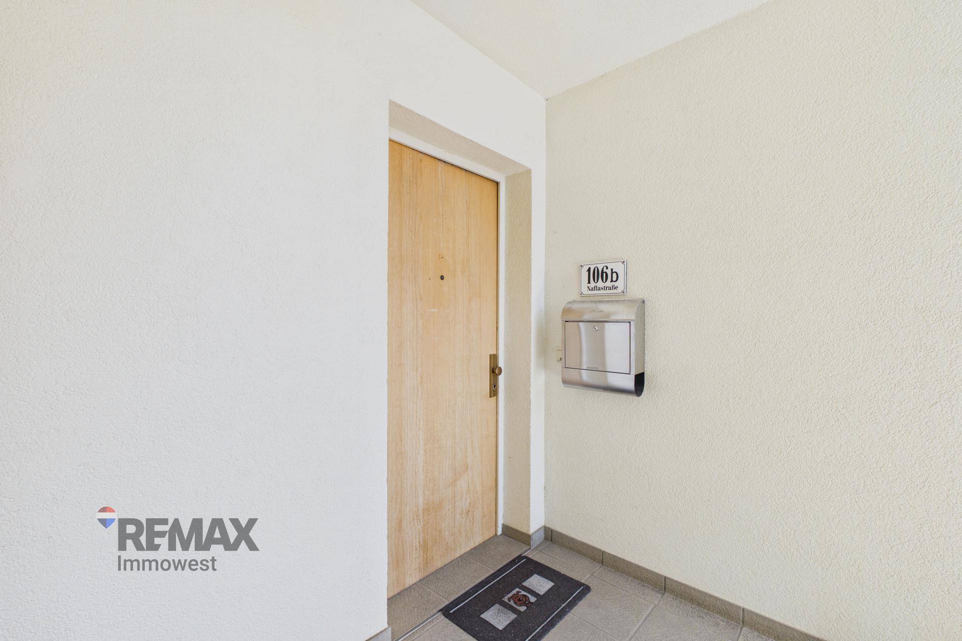 Heller Eingangsbereich einer Wohnung mit Holztür und Briefkasten an der Wand.