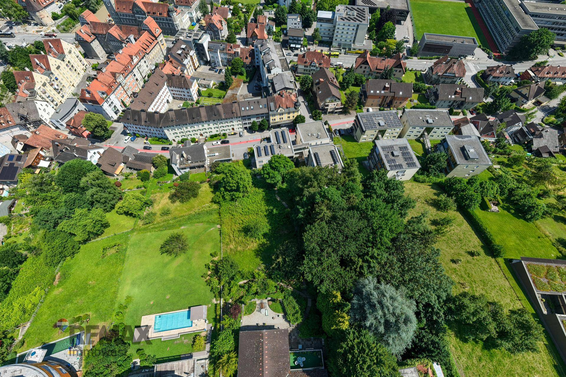 Weitläufige Luftaufnahme einer Stadt mit vielen Gebäuden, Straßen und grünen Flächen.