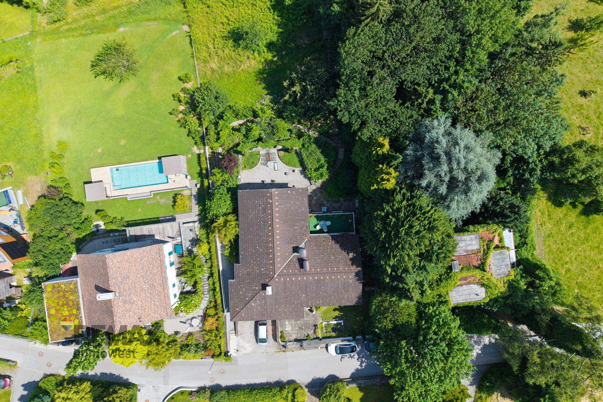 Vogelperspektive eines Anwesens mit großem Haus, gepflegtem Garten und einem Swimmingpool.