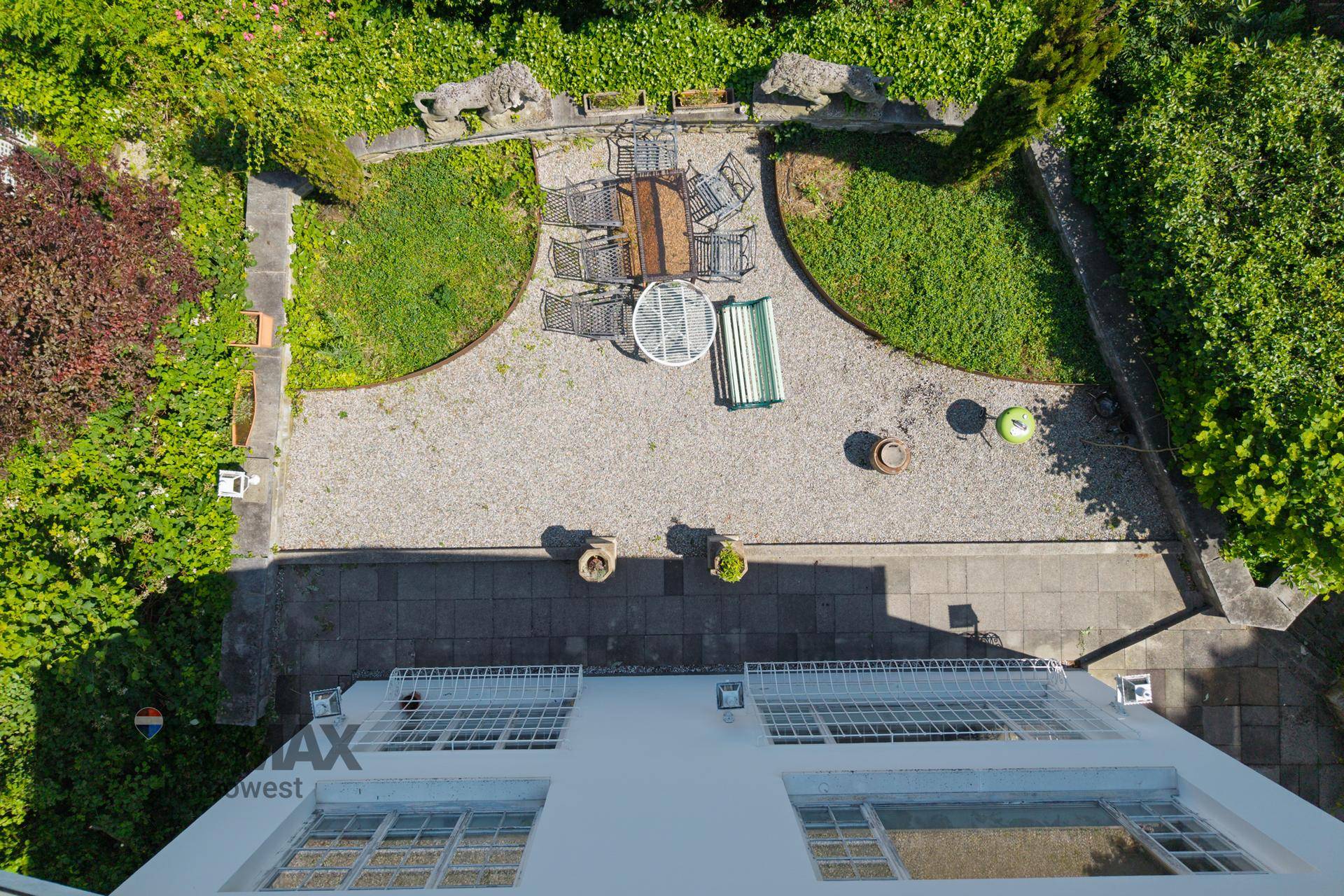 Blick von oben auf den gepflasterten Gartenbereich mit Sitzgelegenheiten und grünen Pflanzen.