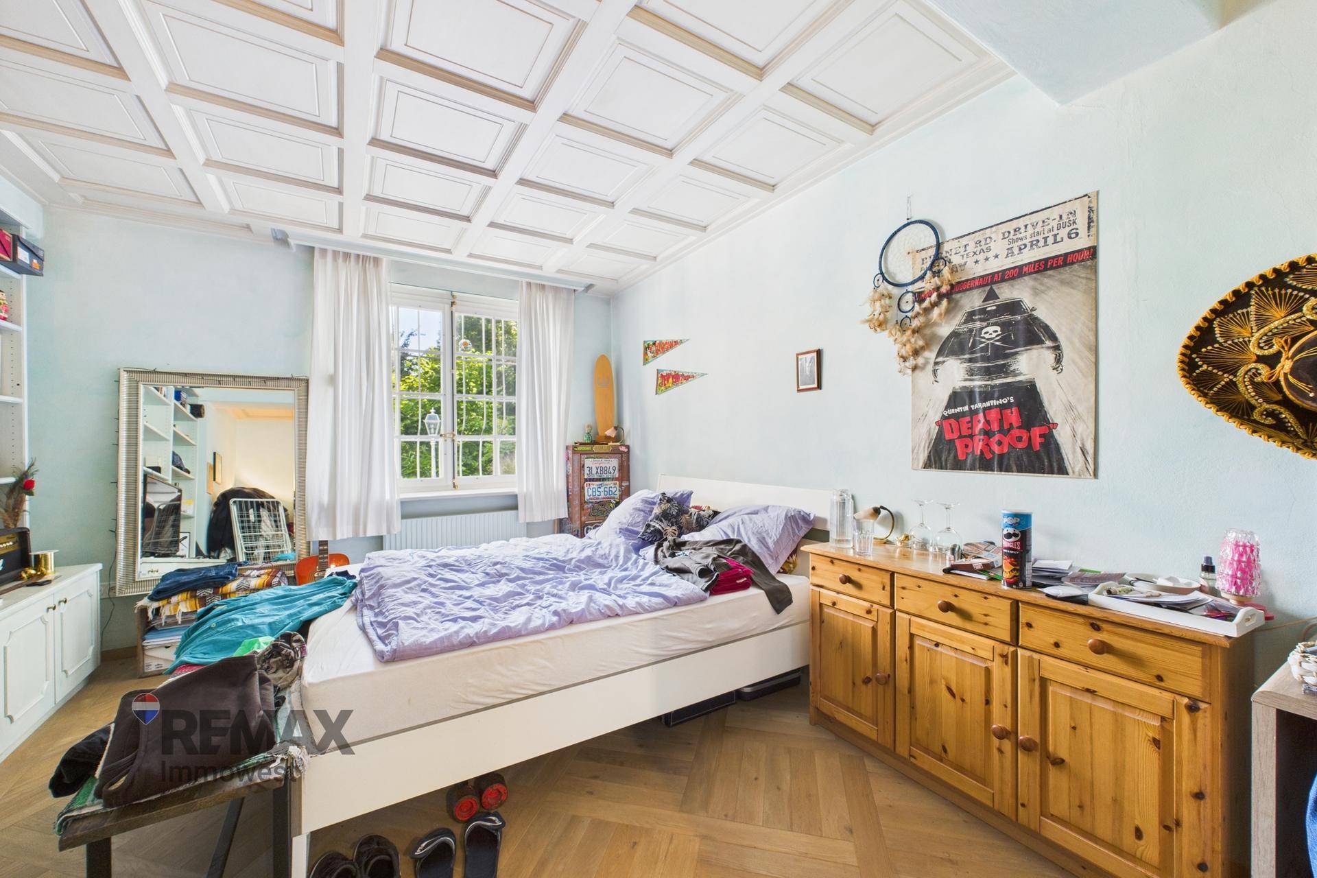 Schlafzimmer mit Holzboden, Holzkastenmöbeln und einer auffälligen Kassettendecke.