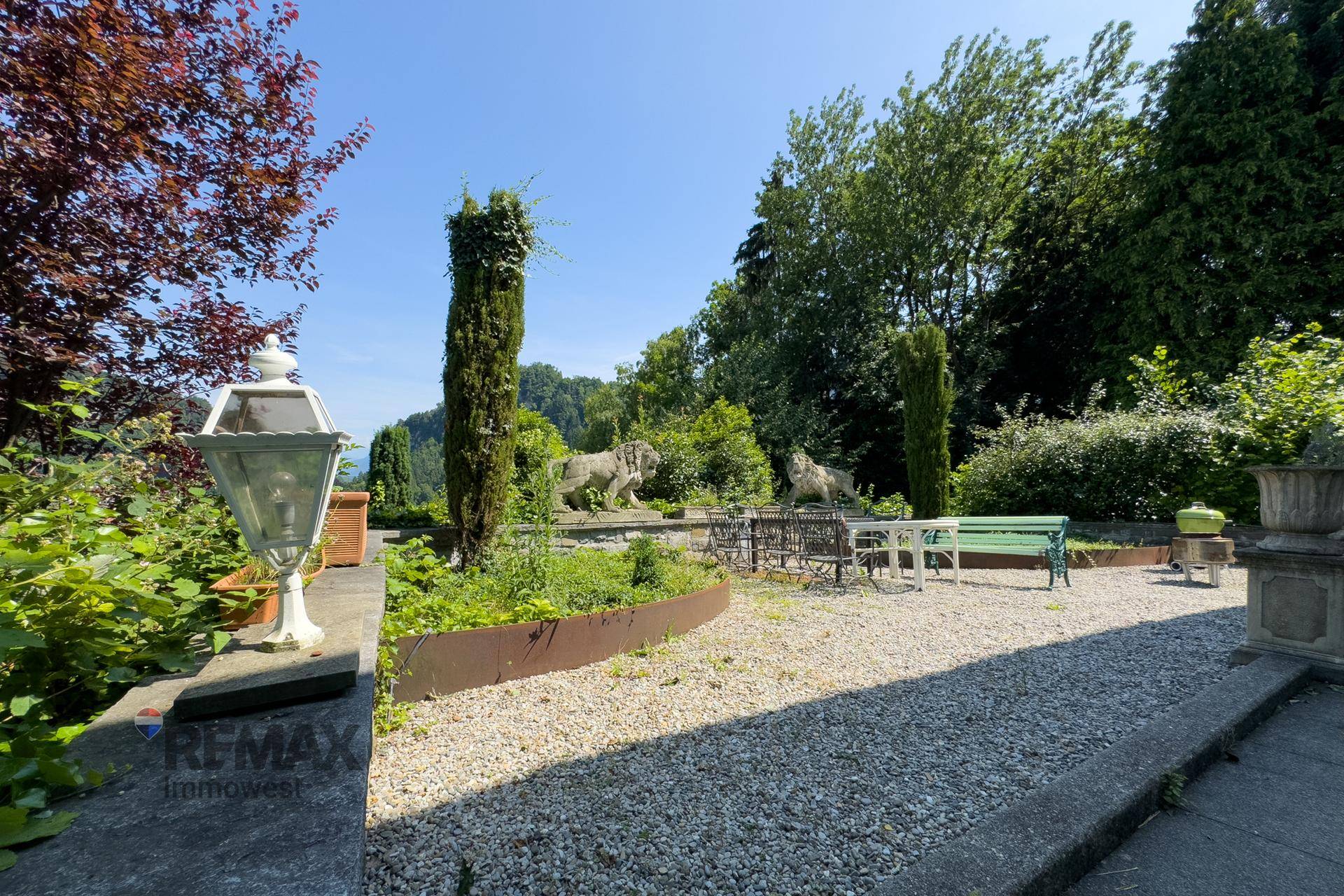 Gartenbereich mit dekorativen Elementen, Sitzgelegenheiten und weitem Blick in die Landschaft.