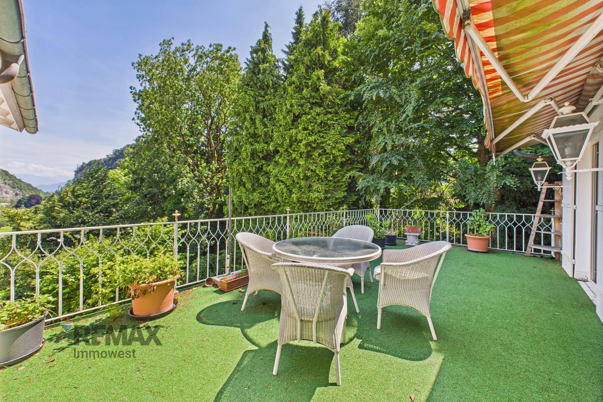 Große Terrasse mit Kunstrasen, Gartenmöbeln und üppiger grüner Umgebung mit Weitblick.