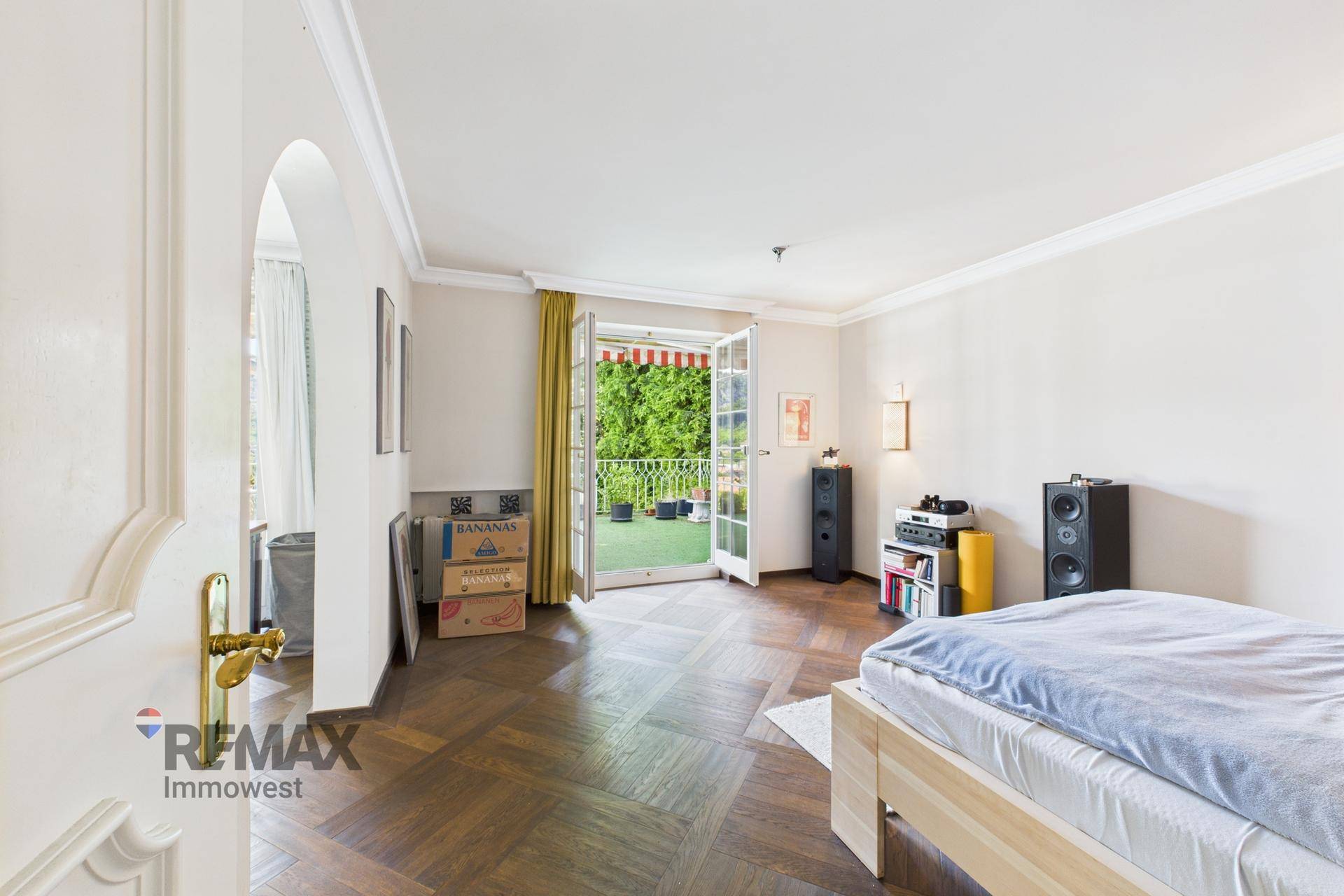 Schlafzimmer mit Parkettboden, Zugang zum Balkon und Blick ins Grüne, hell und geräumig.