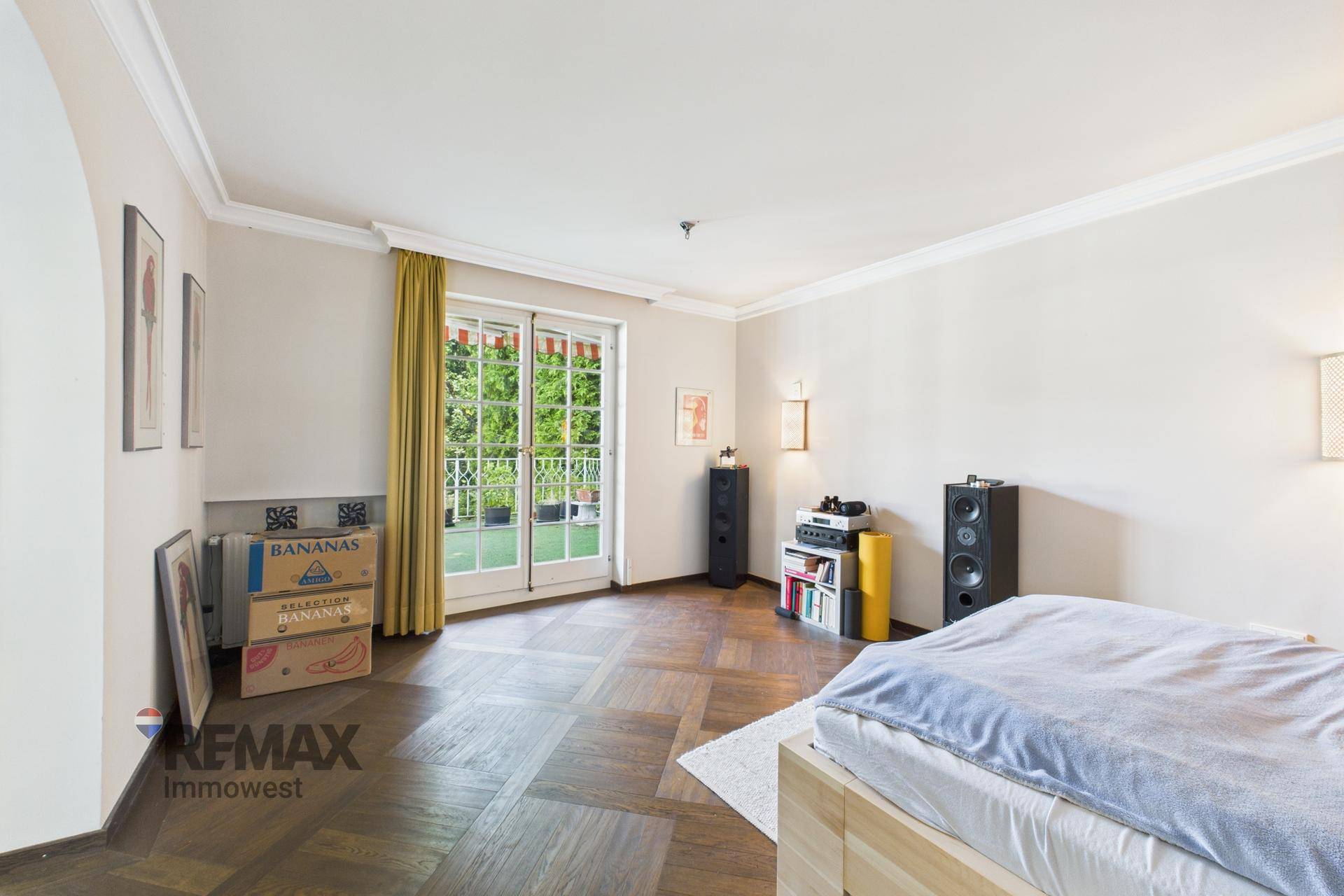 Schlafzimmer mit Parkettboden, hellem Ambiente und Zugang zu einem sonnigen Außenbereich.