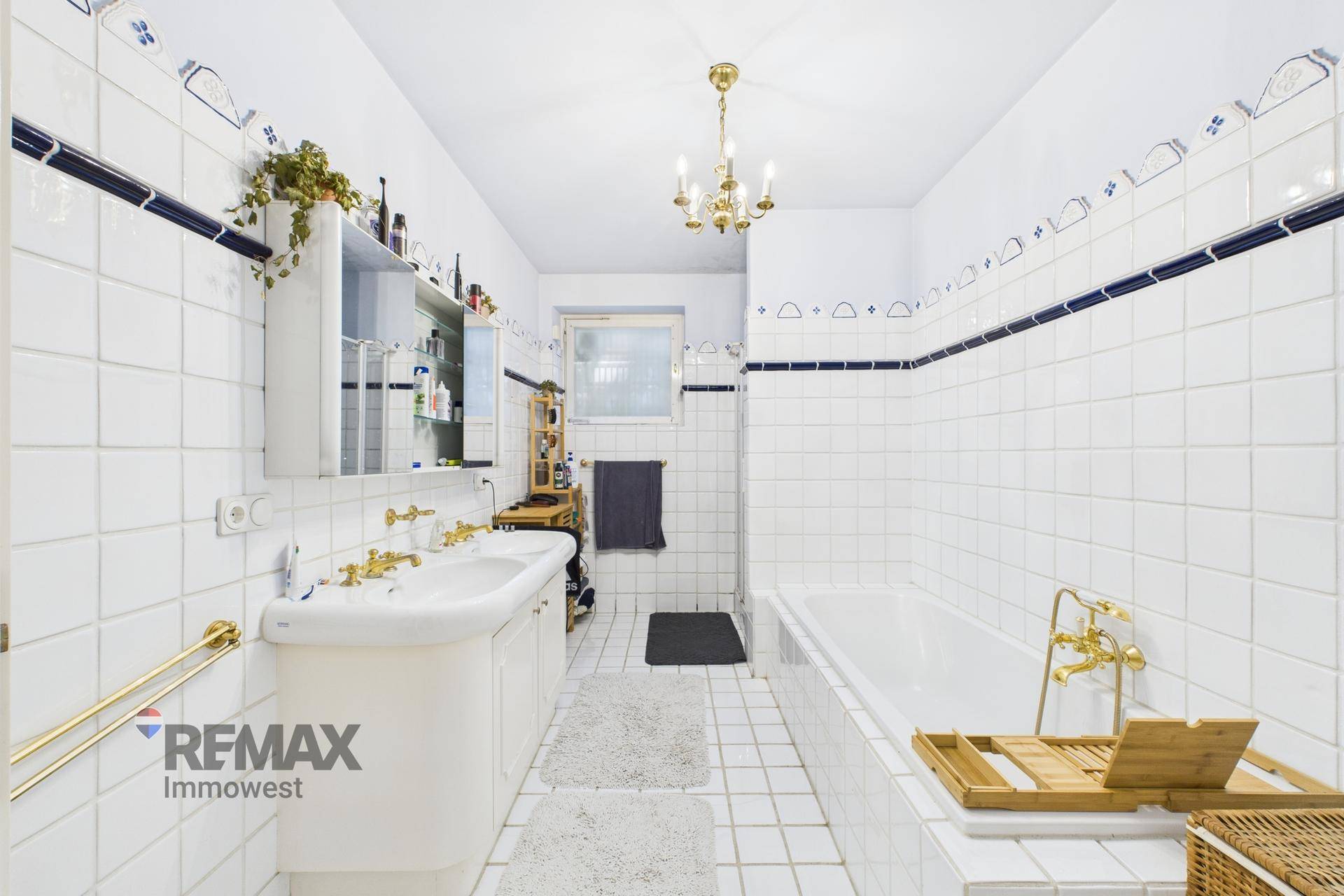 Helles Badezimmer mit weißen Fliesen, Badewanne und Doppelwaschbecken, klassisch eingerichtet.