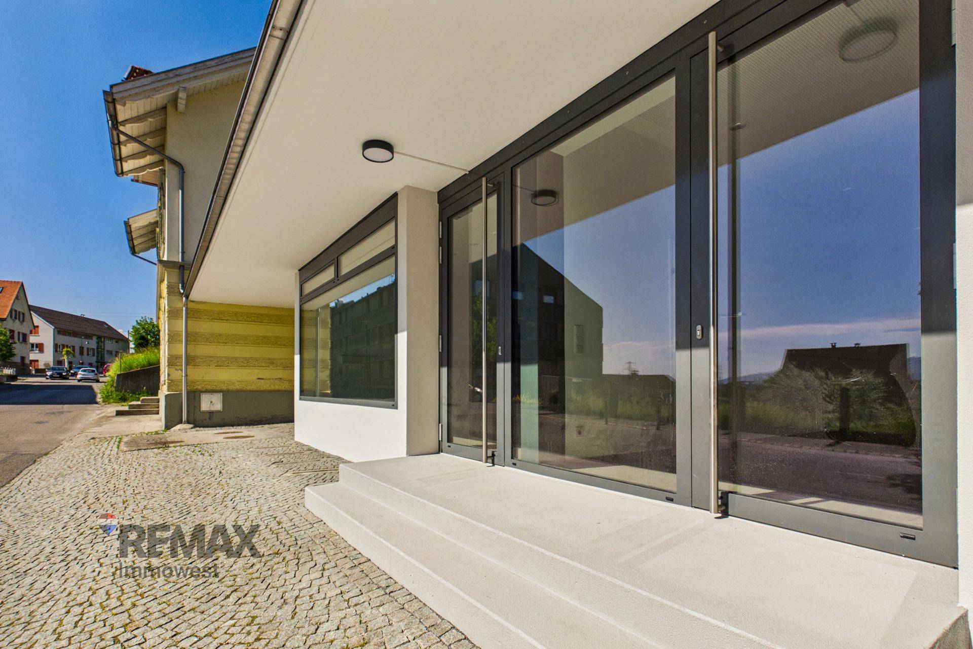 Eingangsbereich der Geschäftsfläche mit großen Glastüren und moderner Architektur.